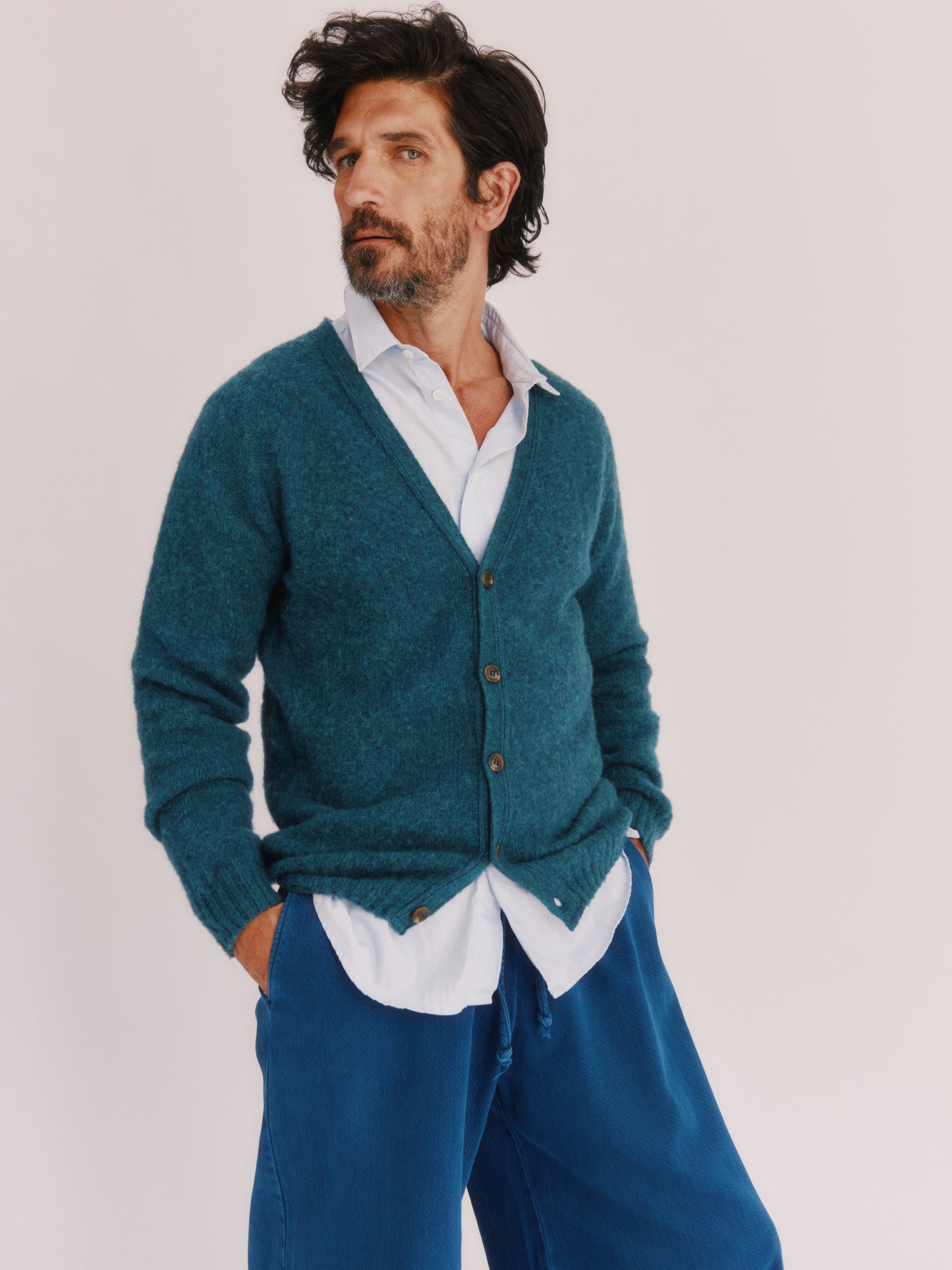 Model wearing a Harley of Scotland Shaggy Shetland Men's V Cardigan in colour Storm Dark Teal.