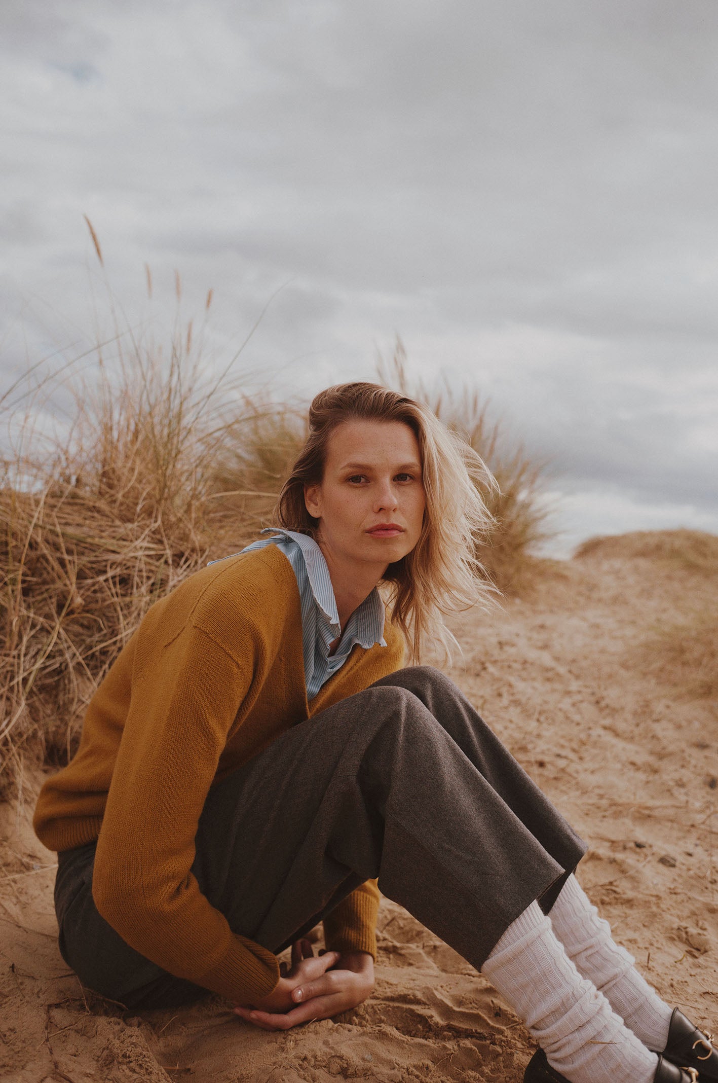 Woman on a beach wearing a Bosie Knitwear Harley x Todd and Duncan boxy premium cashmere cardigan in Smoked Gold
