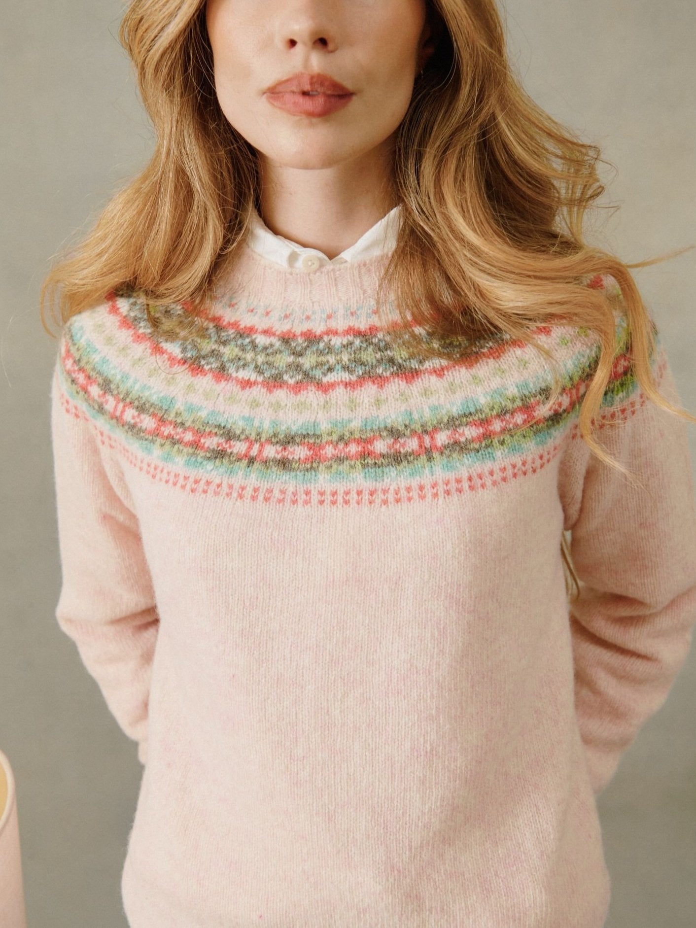 Woman wearing a strawberry sherbert pink Bosie Skye Lambswool Fairisle Yoke Sweater.