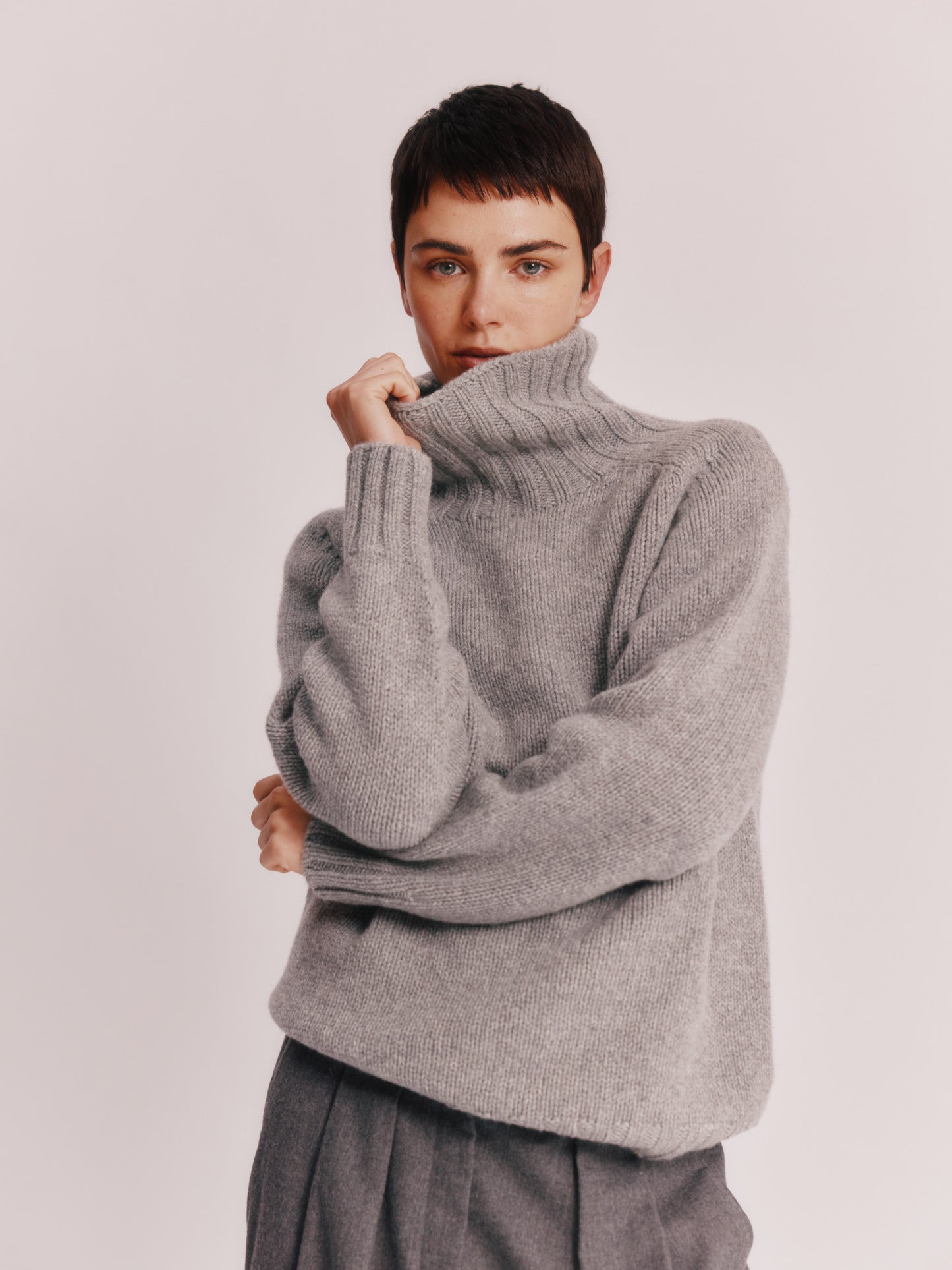 Model wearing a Bosie Knitwear Blue Mogganer Womens Siren Merino Polo Neck Sweater in colour Flannel Grey.