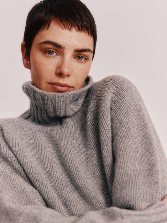 Model wearing a Bosie Knitwear Blue Mogganer Womens Siren Merino Polo Neck Sweater in colour Flannel Grey.