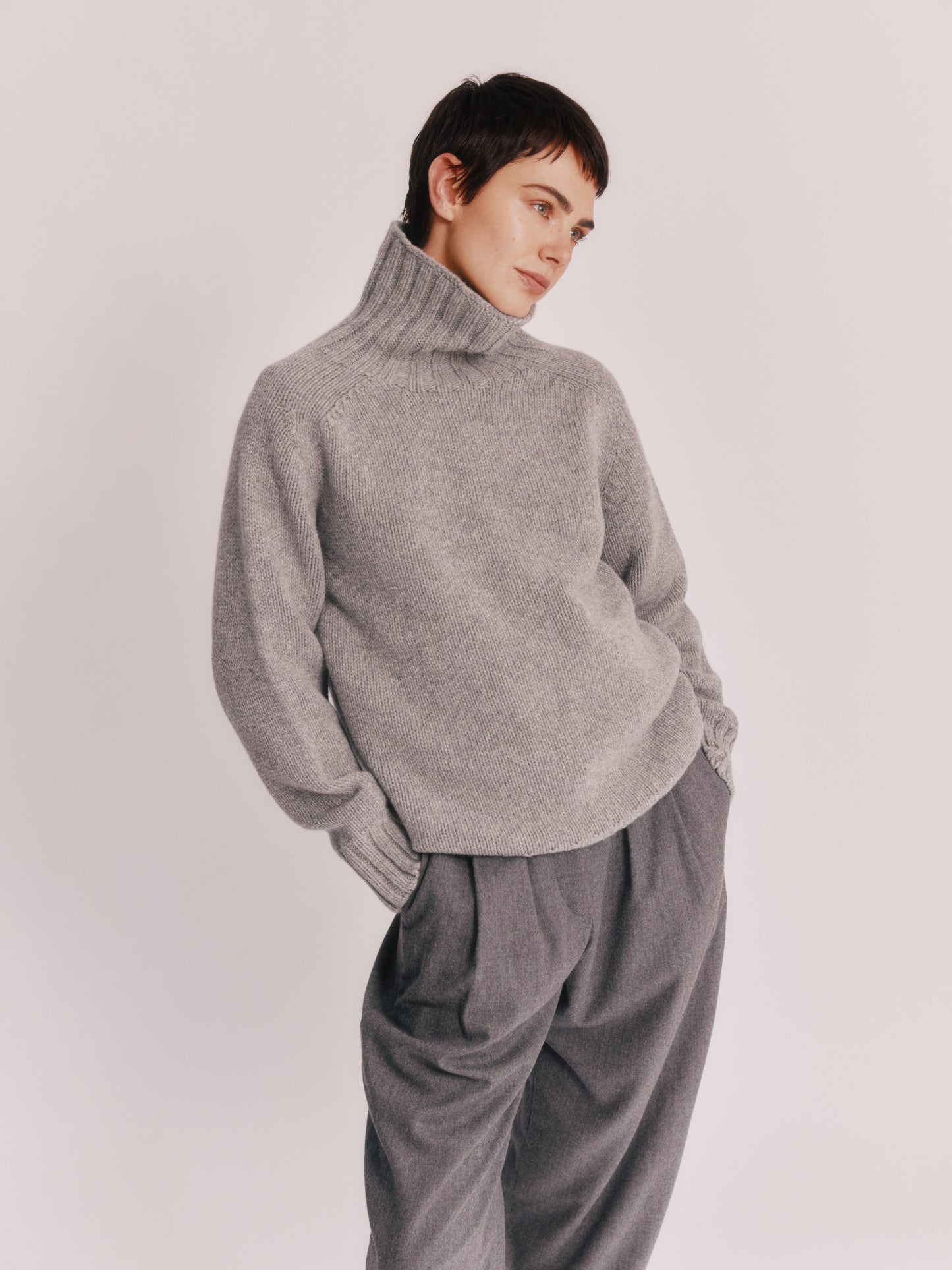 Model wearing a Bosie Knitwear Blue Mogganer Womens Siren Merino Polo Neck Sweater in colour Flannel Grey.