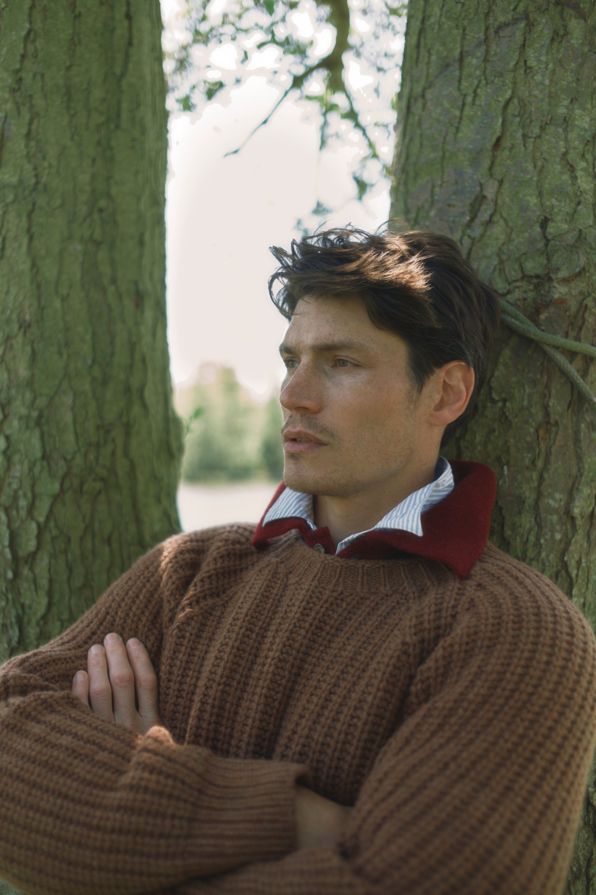 Man leaning against a tree in a natural setting wearing Bosie Blue Mogganer Fishermans Sweater