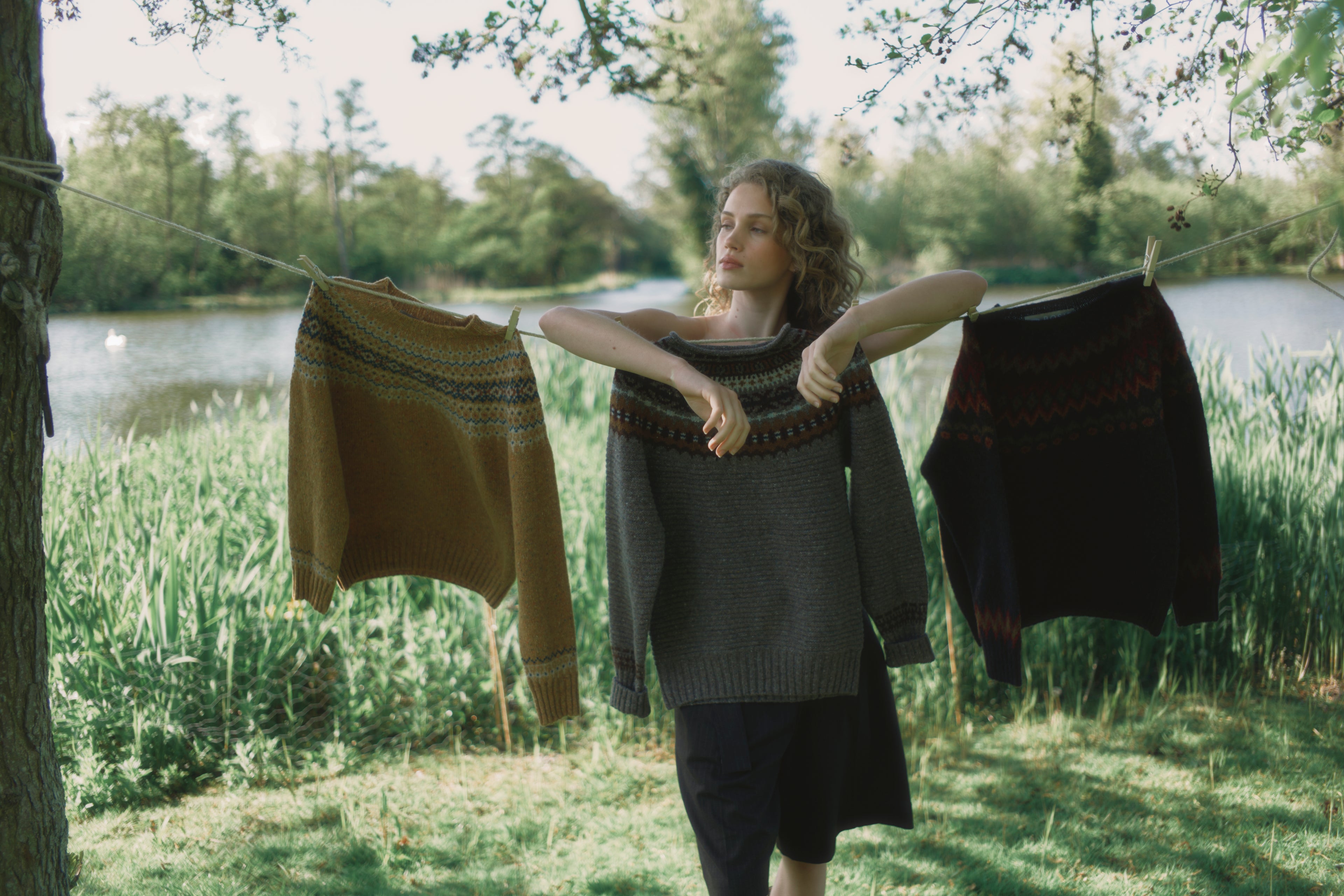 Woman hanging clothes on a line by a lake
