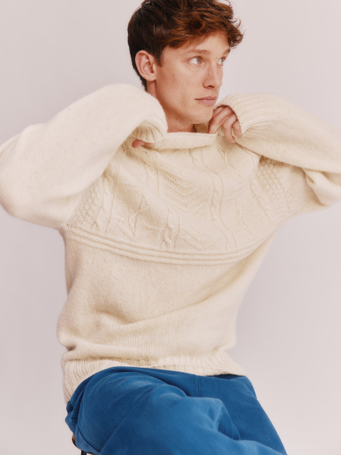 Model wearing a Bosie Knitwear Blue Mogganer Ganjey Heritage Heather Knoll Crew Neck Sweater in colour Ecru White.