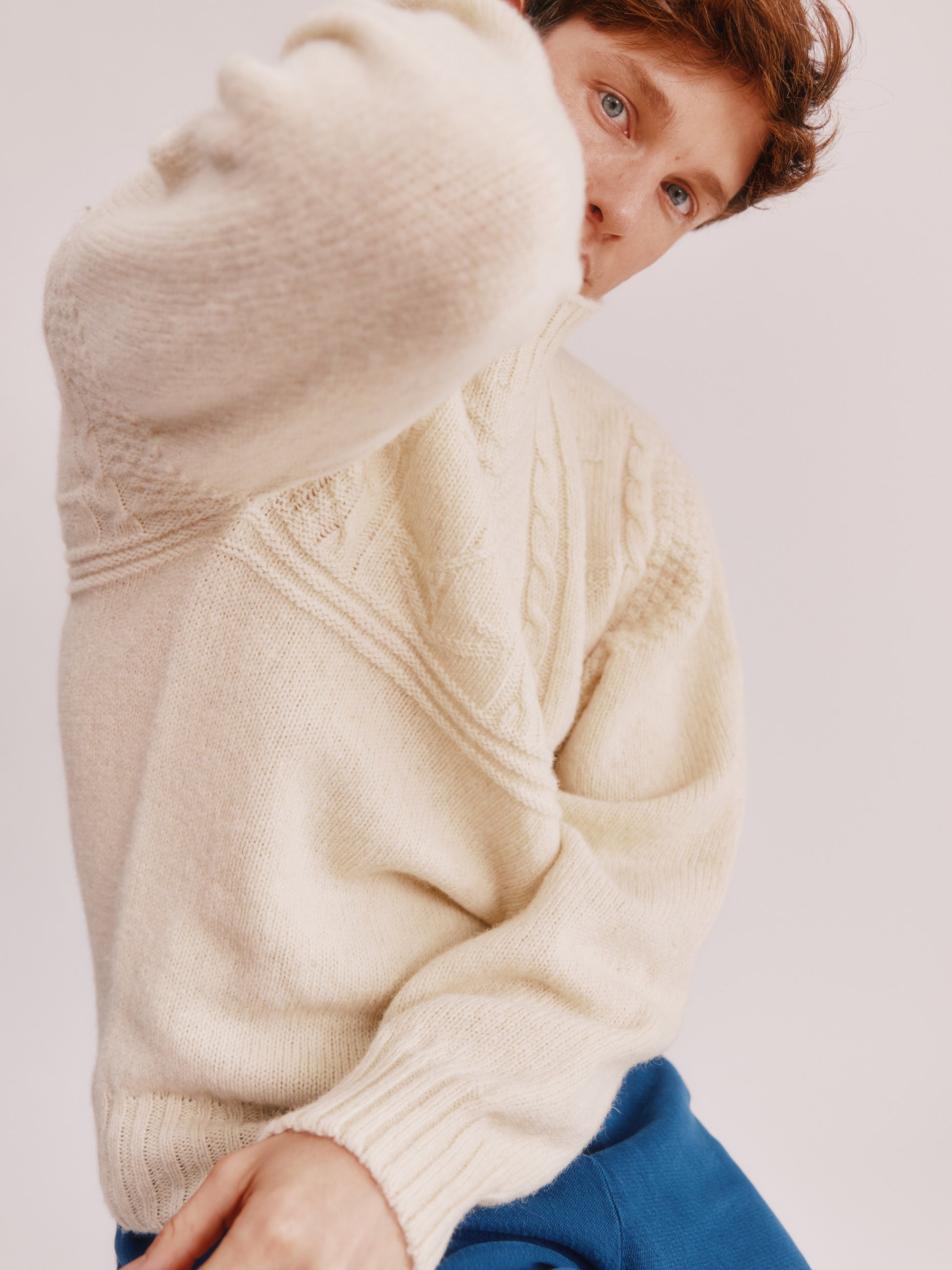 Model wearing a Bosie Knitwear Blue Mogganer Ganjey Heritage Heather Knoll Crew Neck Sweater in colour Ecru White.