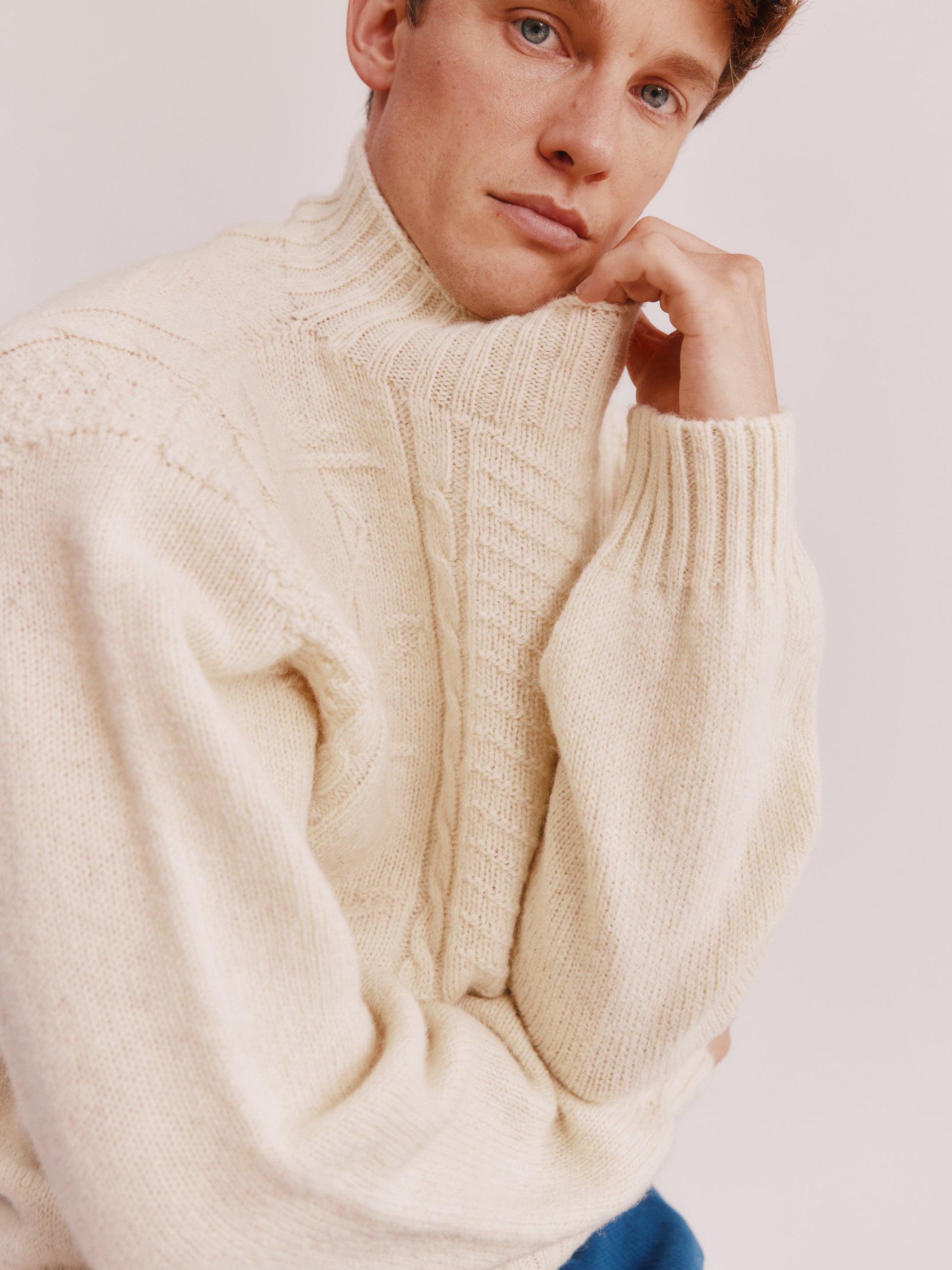 Model wearing a Bosie Knitwear Blue Mogganer Ganjey Heritage Heather Knoll Crew Neck Sweater in colour Ecru White.