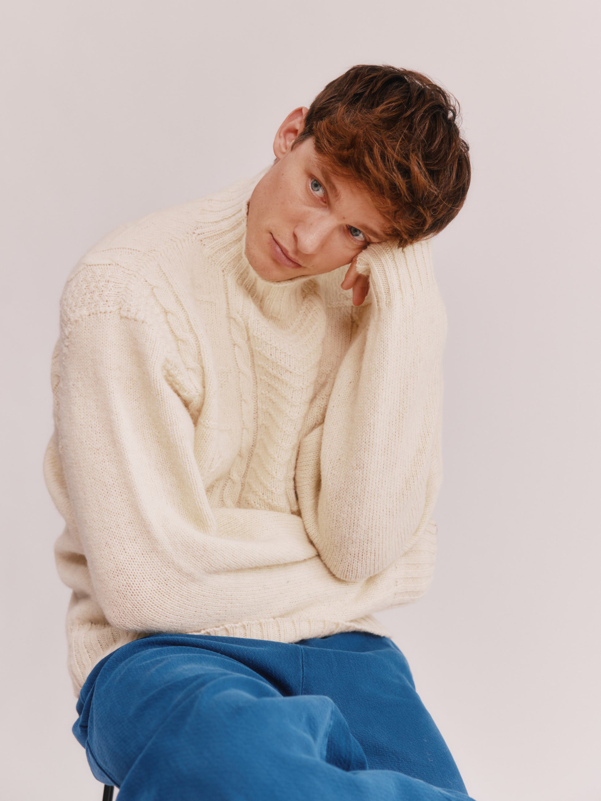 Model wearing a Bosie Knitwear Blue Mogganer Ganjey Heritage Heather Knoll Crew Neck Sweater in colour Ecru White.