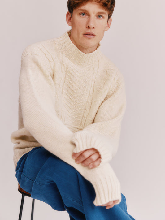 Model wearing a Bosie Knitwear Blue Mogganer Ganjey Heritage Heather Knoll Crew Neck Sweater in colour Ecru White.