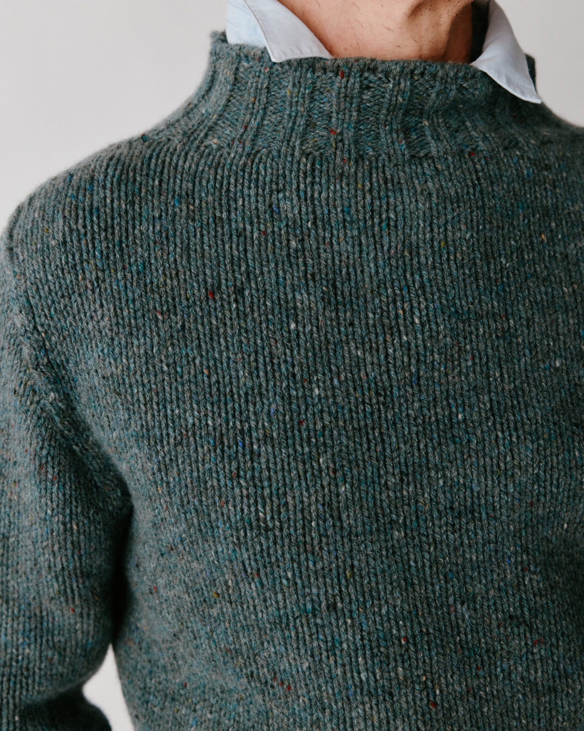 A model wearing a Bosie Blue Mogganer Glenugie Nep Funnel Neck Lighthouse Sweater in colour Lomond.