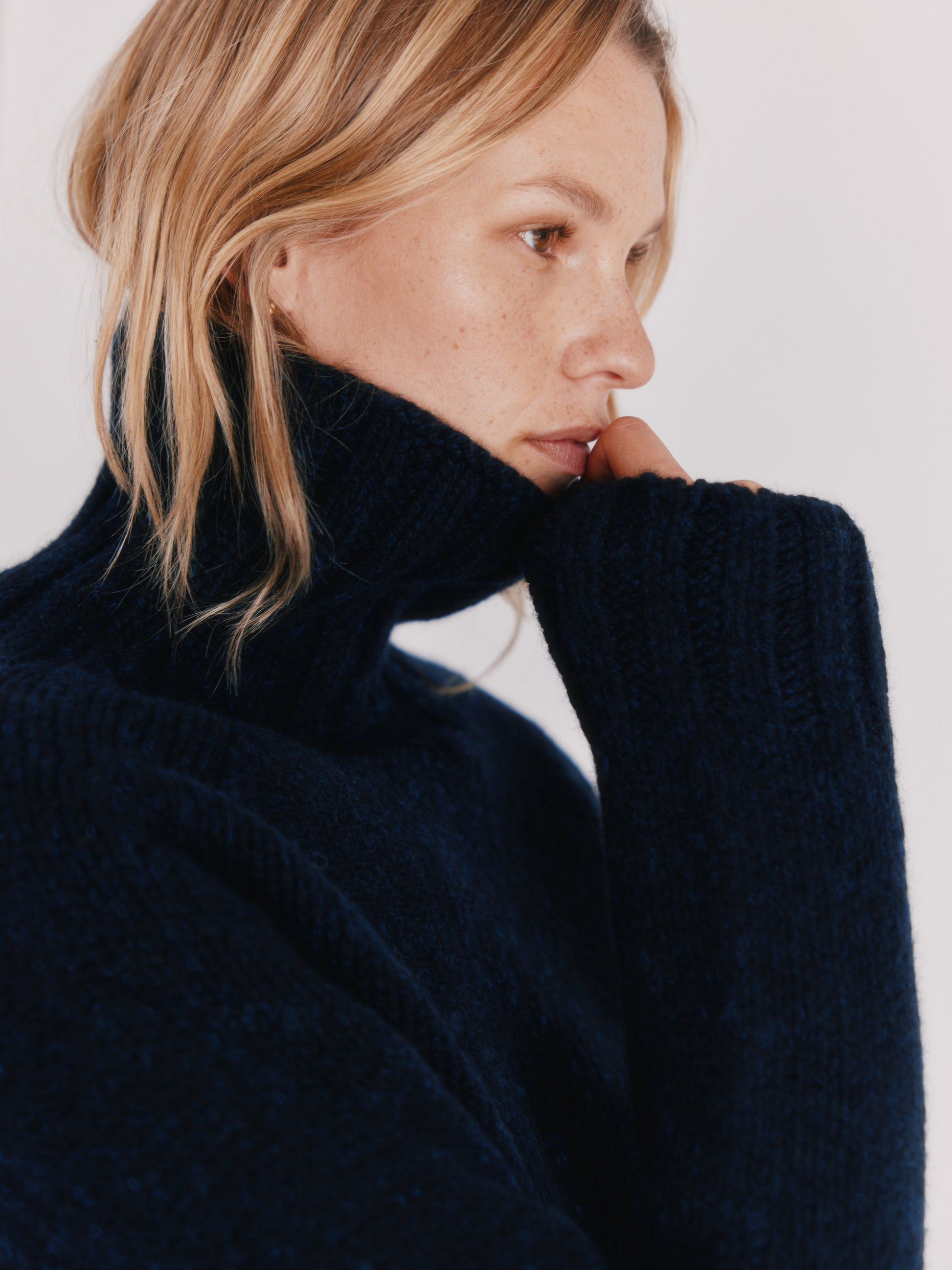 Woman wearing a Blue Mogganer Cosmos Navy Siren fishermas chunky roll polo neck in Geelong merino by Bosie Knitwear.