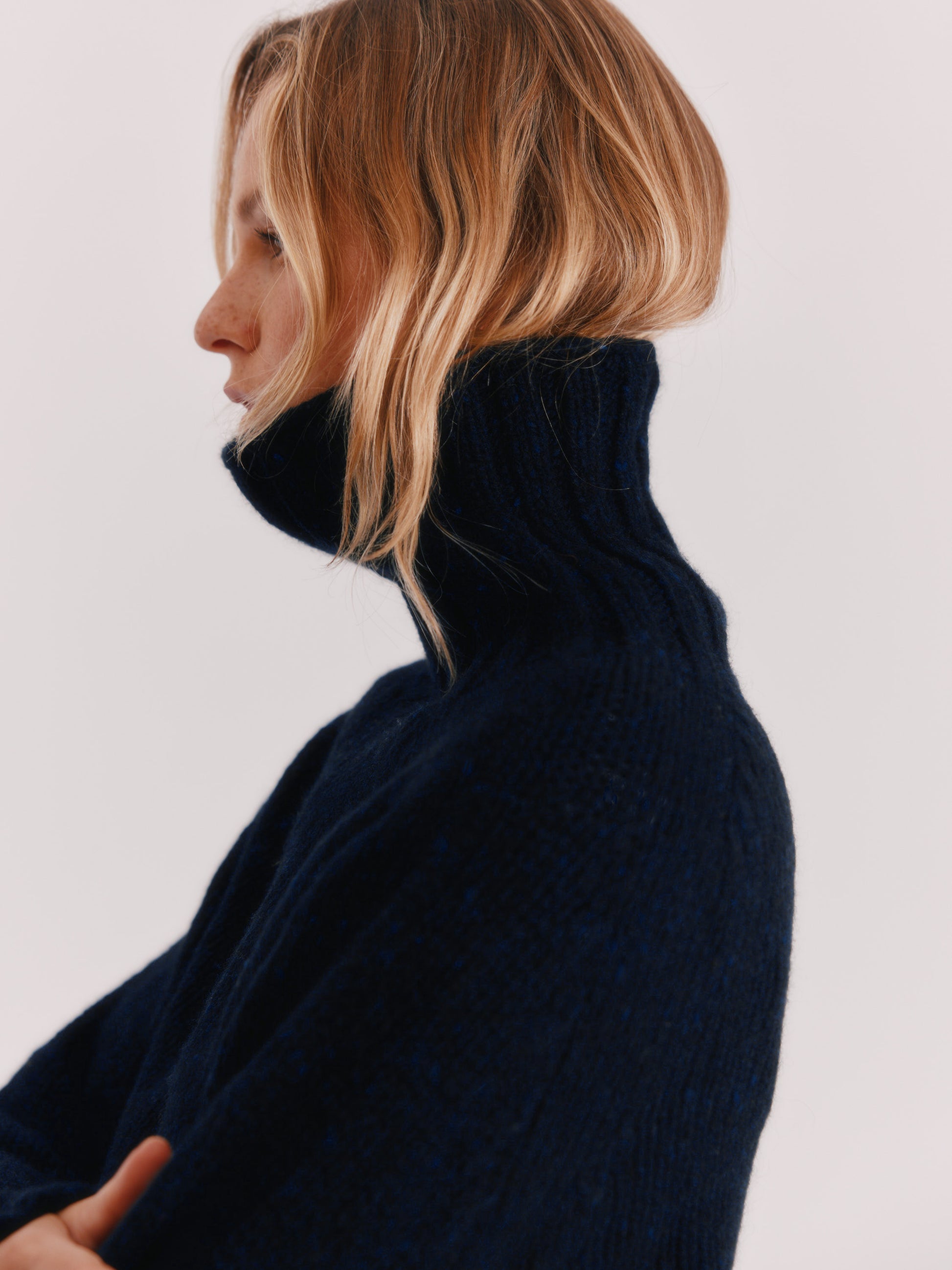 Woman wearing a Blue Mogganer Cosmos Navy Siren fishermas chunky roll polo neck in Geelong merino by Bosie Knitwear.