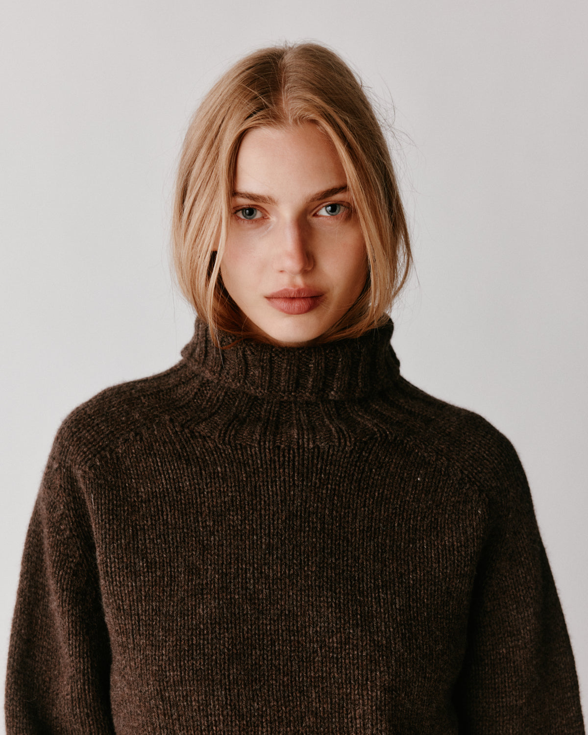 A model wearing a Bosie Blue Mogganer Womens Siren Merino Polo Neck Sweater in colour Porcupine.