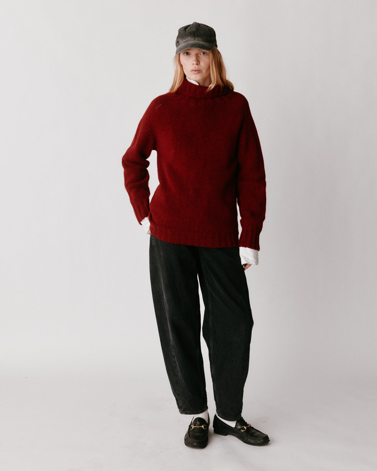 A model wearing a Bosie Blue Mogganer Womens Siren Merino Polo Neck Sweater in colour Russet Red.
