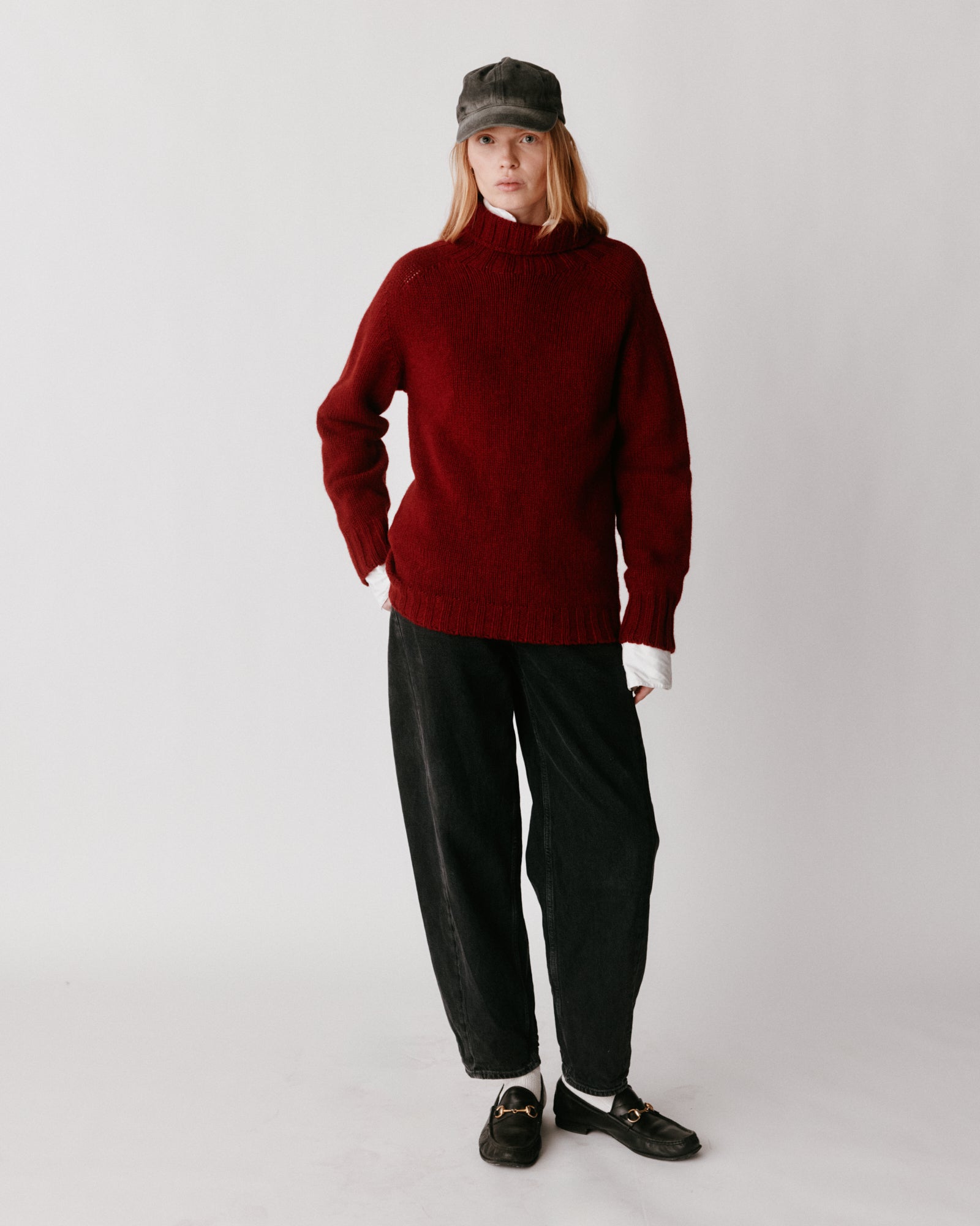 A model wearing a Bosie Blue Mogganer Womens Siren Merino Polo Neck Sweater in colour Russet Red.