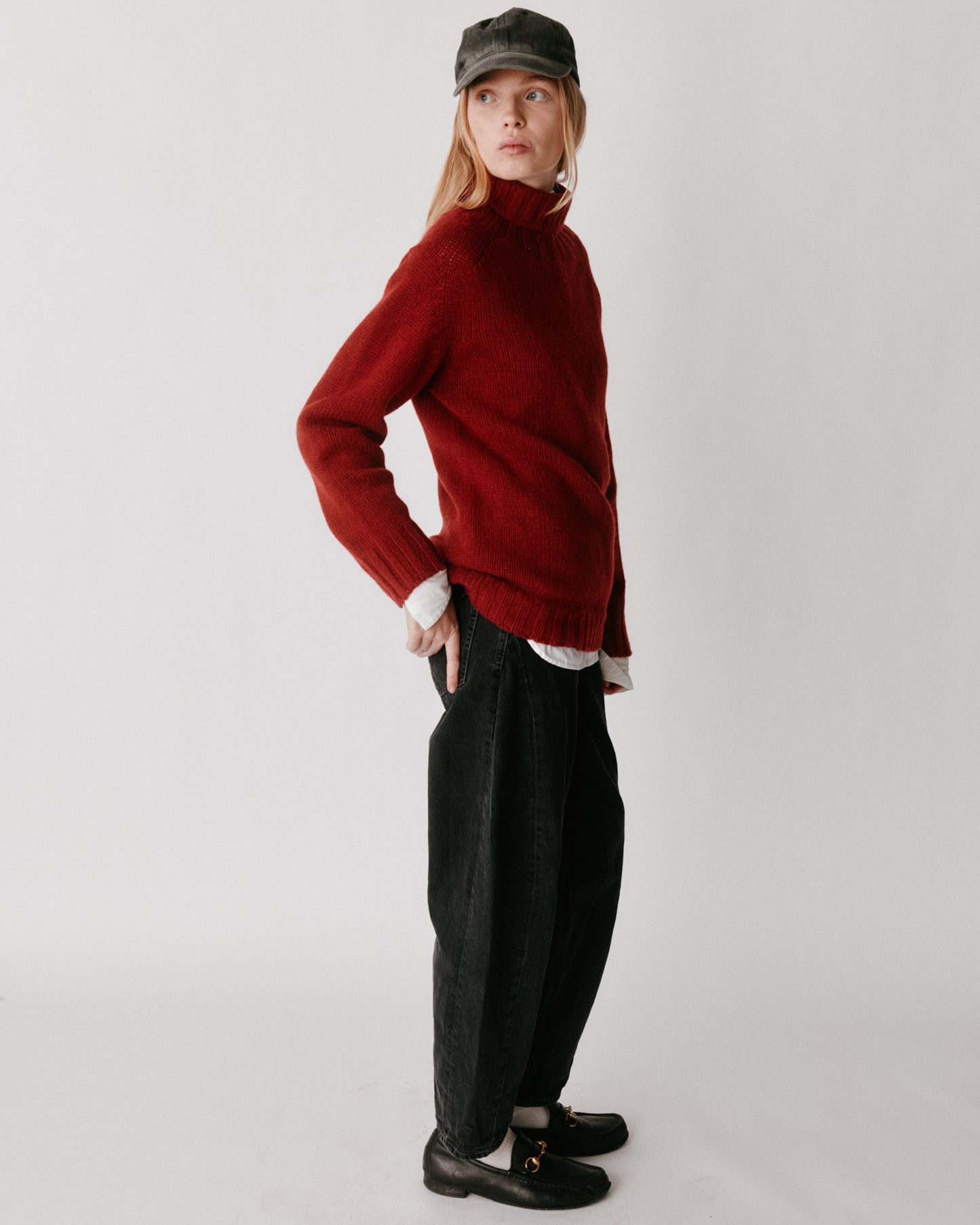 A model wearing a Bosie Blue Mogganer Womens Siren Merino Polo Neck Sweater in colour Russet Red.