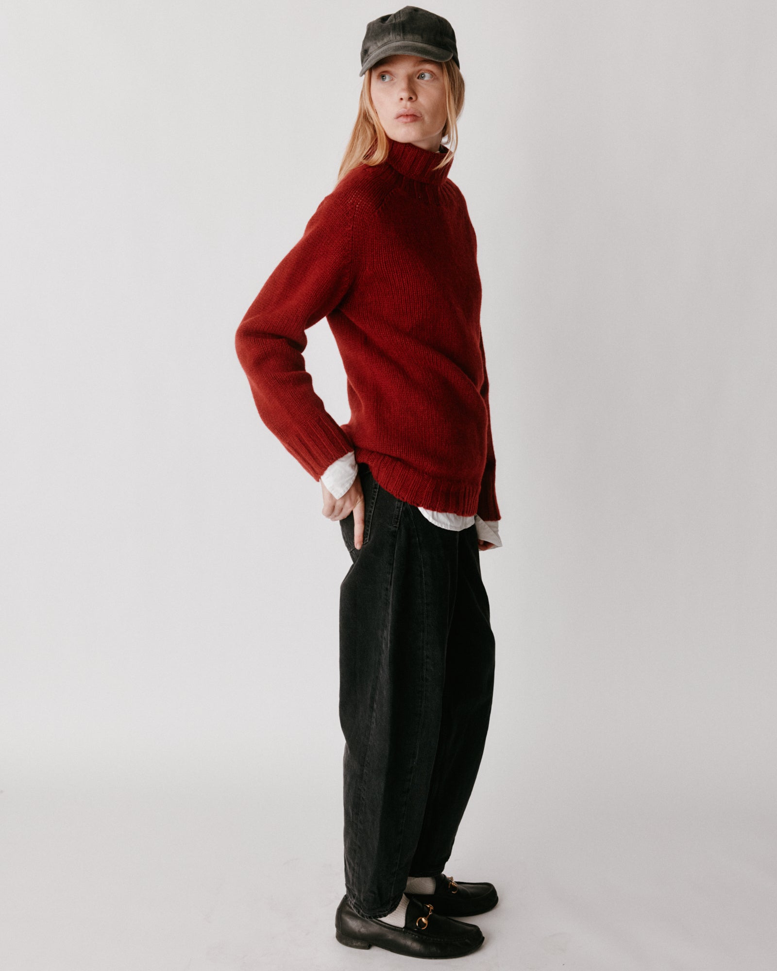 A model wearing a Bosie Blue Mogganer Womens Siren Merino Polo Neck Sweater in colour Russet Red.