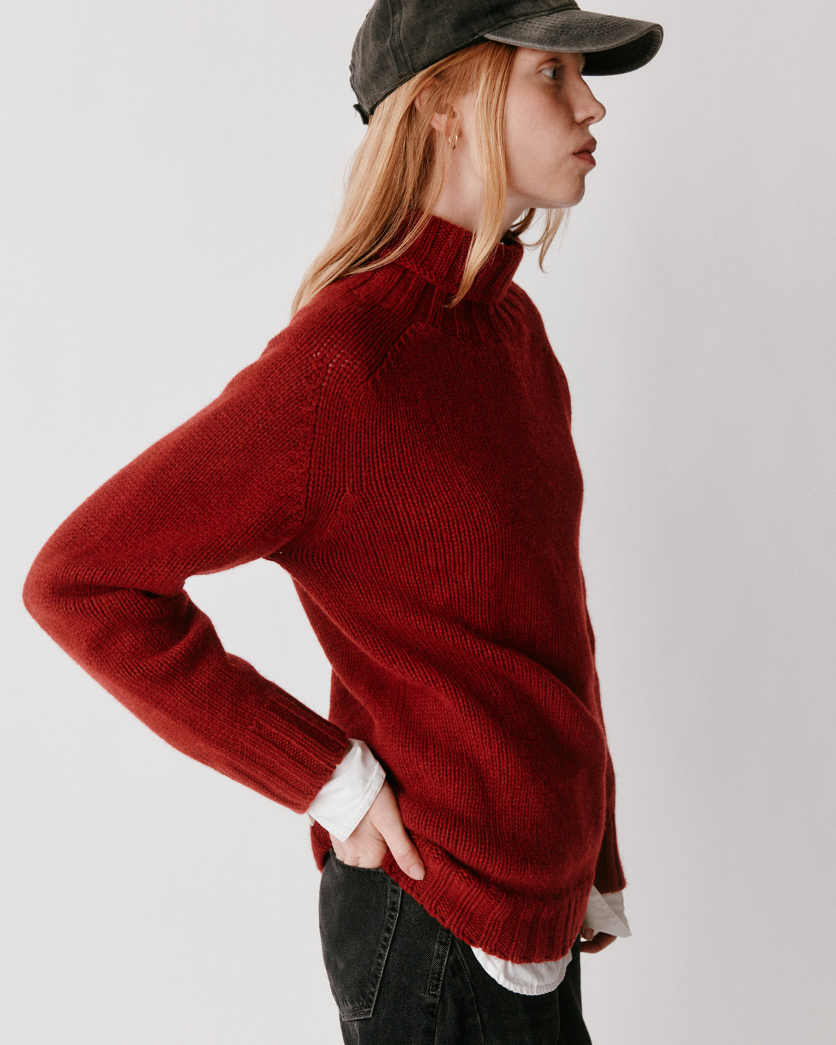A model wearing a Bosie Blue Mogganer Womens Siren Merino Polo Neck Sweater in colour Russet Red.