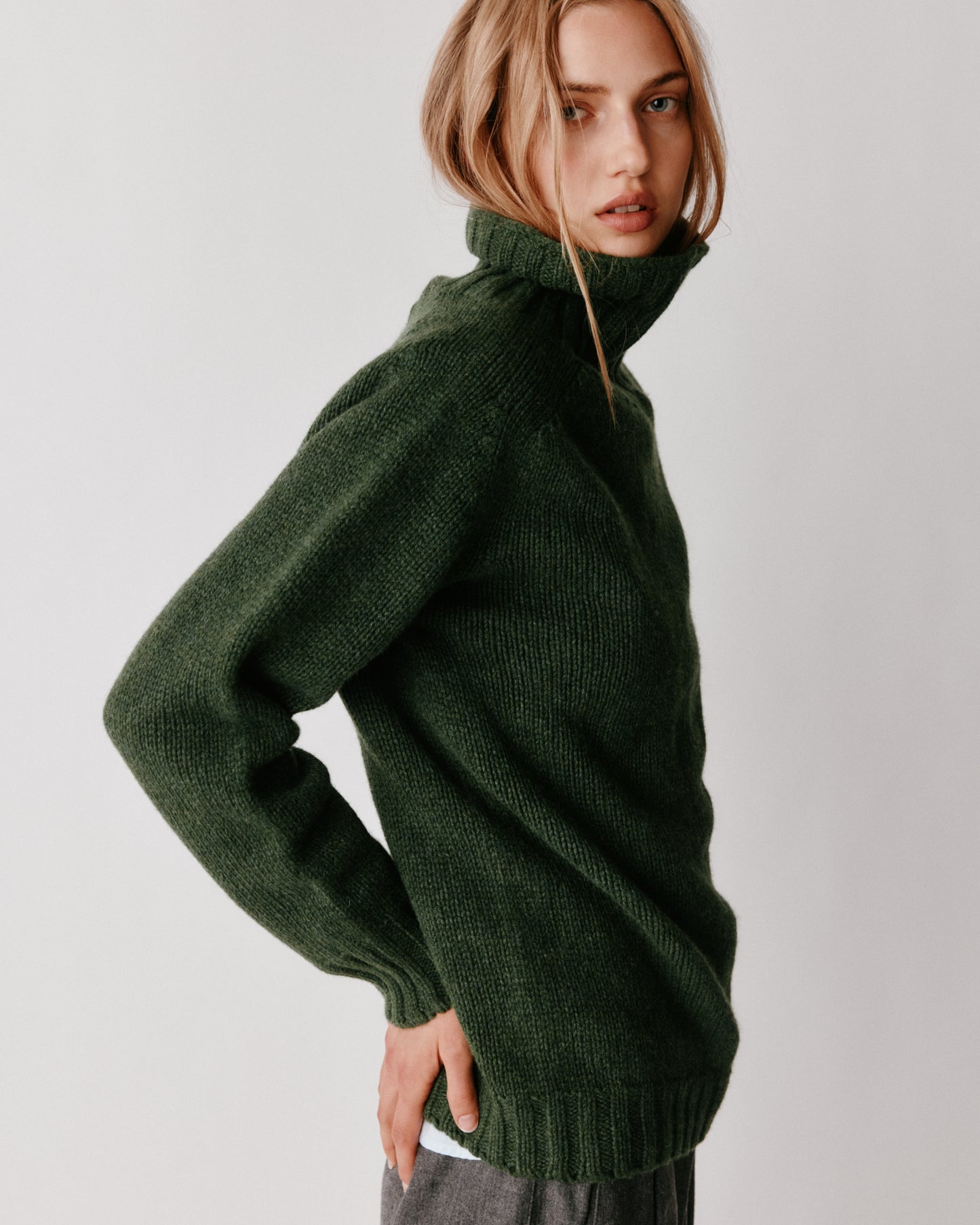 A model wearing a Bosie Blue Mogganer Womens Siren Merino Polo Neck Sweater in colour Serpentine.