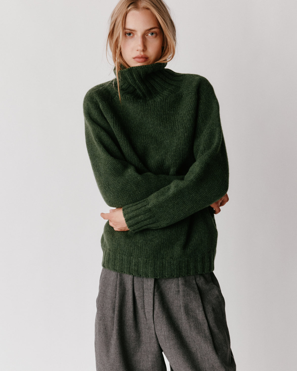 A model wearing a Bosie Blue Mogganer Womens Siren Merino Polo Neck Sweater in colour Serpentine.