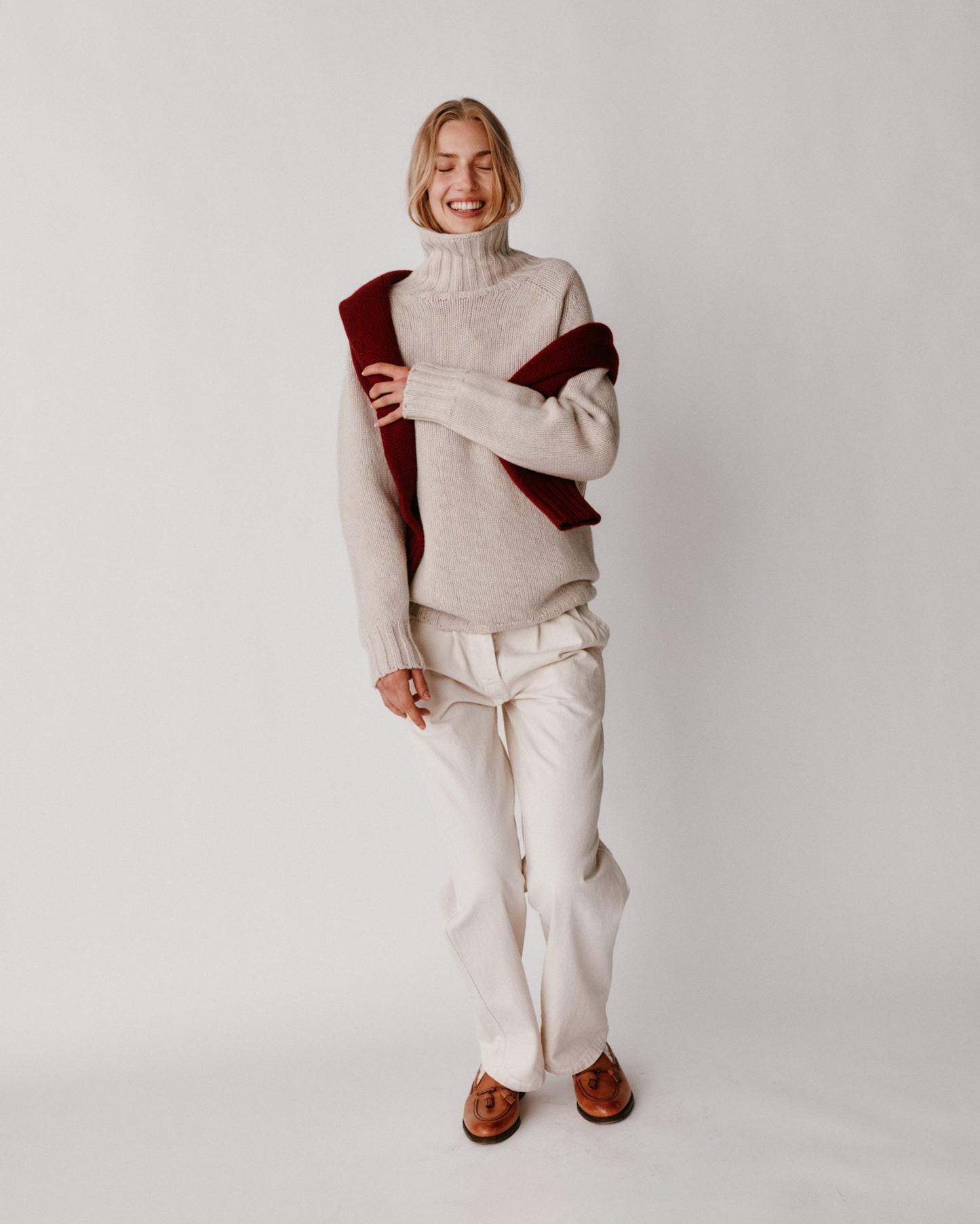 A model wearing a Bosie Blue Mogganer Womens Siren Merino Polo Neck Sweater in colour Swansdown.