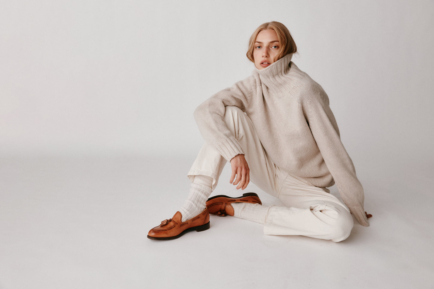 A model wearing a Bosie Blue Mogganer Womens Siren Merino Polo Neck Sweater in colour Swansdown.