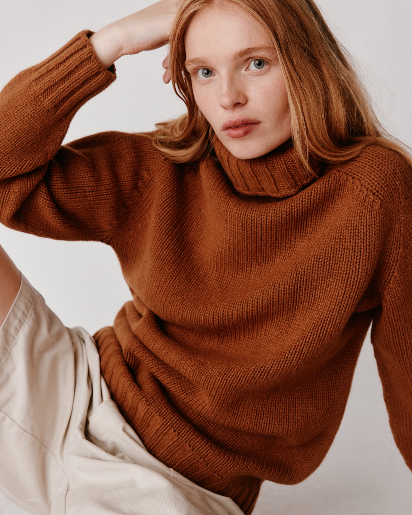 A model wearing a Bosie Blue Mogganer Womens Siren Merino Polo Neck Sweater in colour Vintage Vicuna.