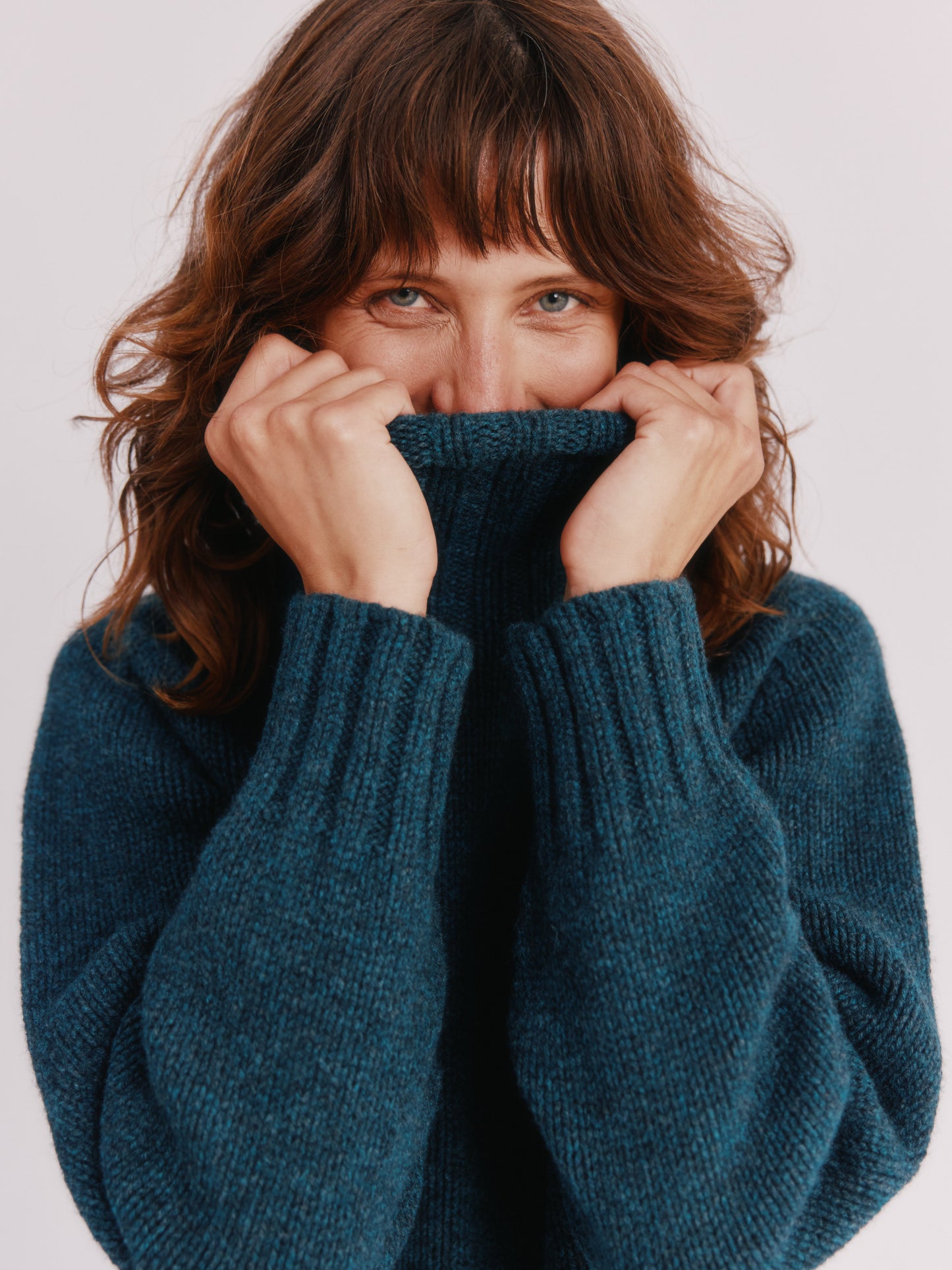 Model wearing a Bosie Knitwear Blue Mogganer Womens Siren Merino Polo Neck Sweater in colour Lugano Dark Teal.