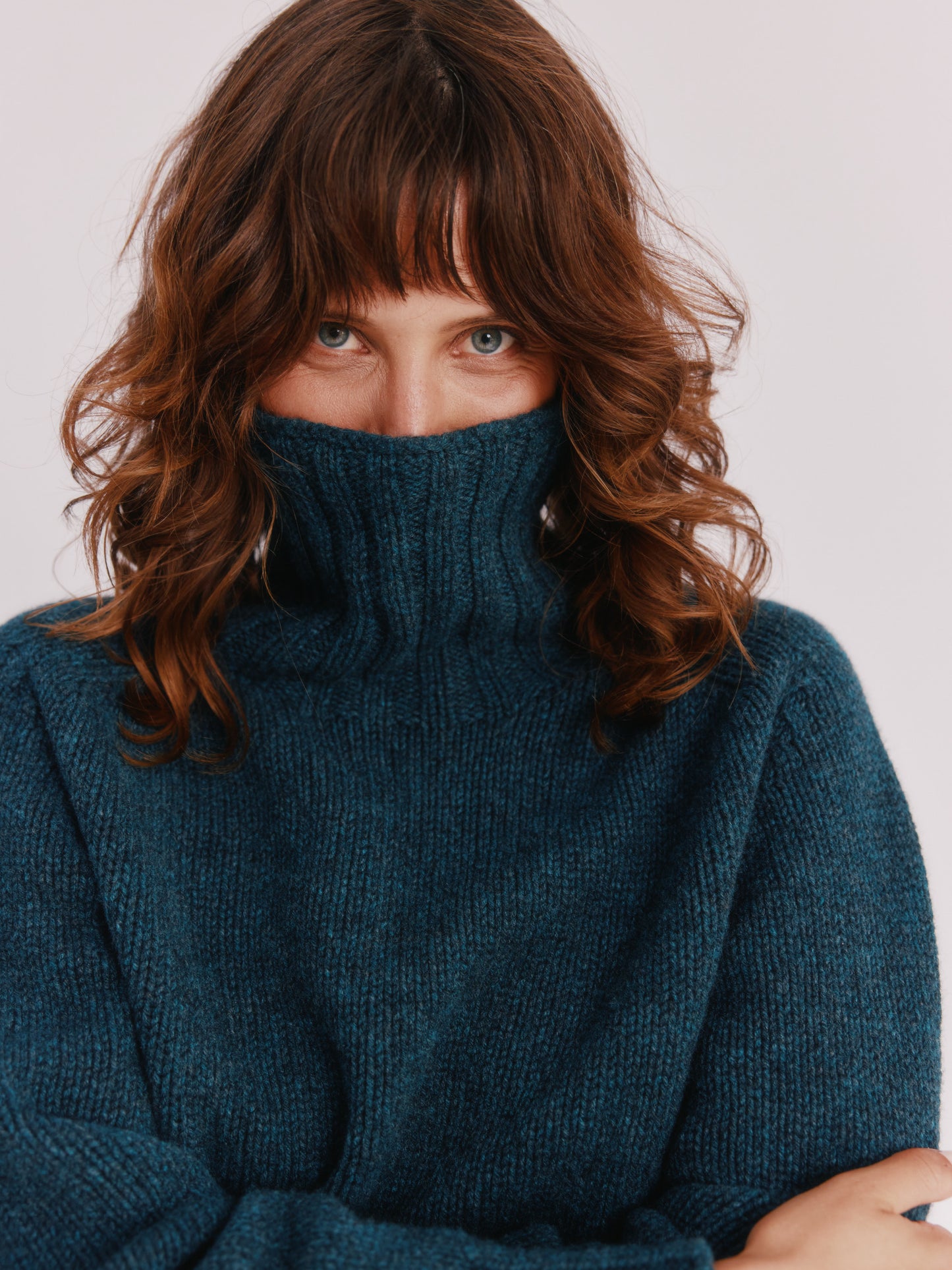 Model wearing a Bosie Knitwear Blue Mogganer Womens Siren Merino Polo Neck Sweater in colour Lugano Dark Teal.