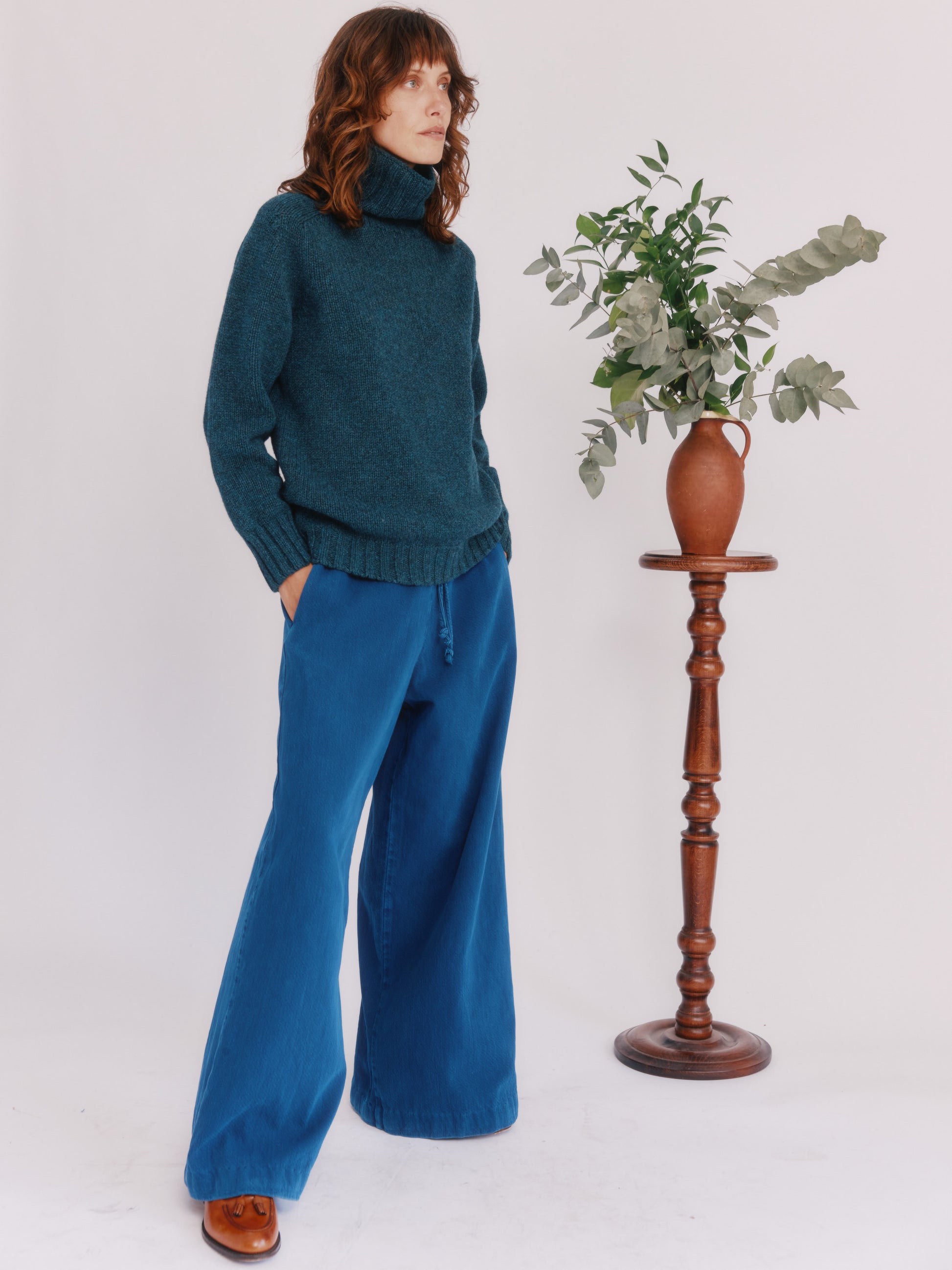 Model wearing a Bosie Knitwear Blue Mogganer Womens Siren Merino Polo Neck Sweater in colour Lugano Dark Teal.