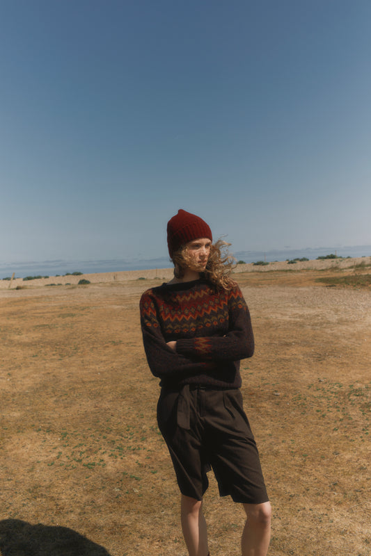 Model wearing a Bosie Brushed Shetland Wool Beanie Hat in colour Claret / Bordeaux MIx in a field. 