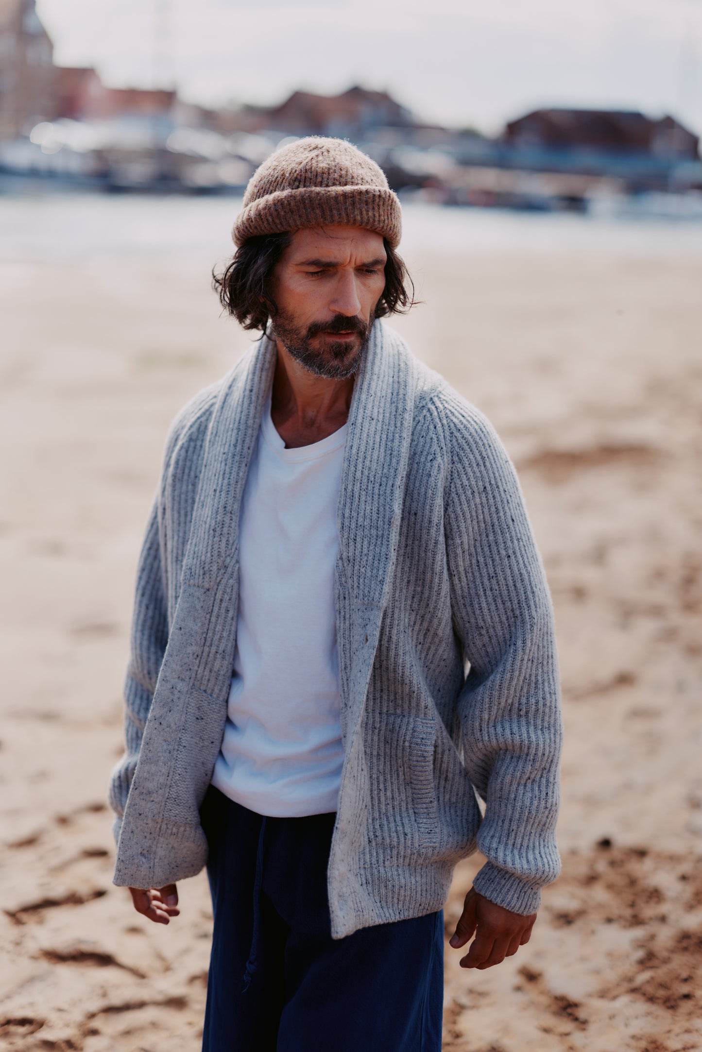Man wearing a  Bosie Blue Mogganer Harbourmaster Cardigan and Heathland Brushed wool hat on a beach