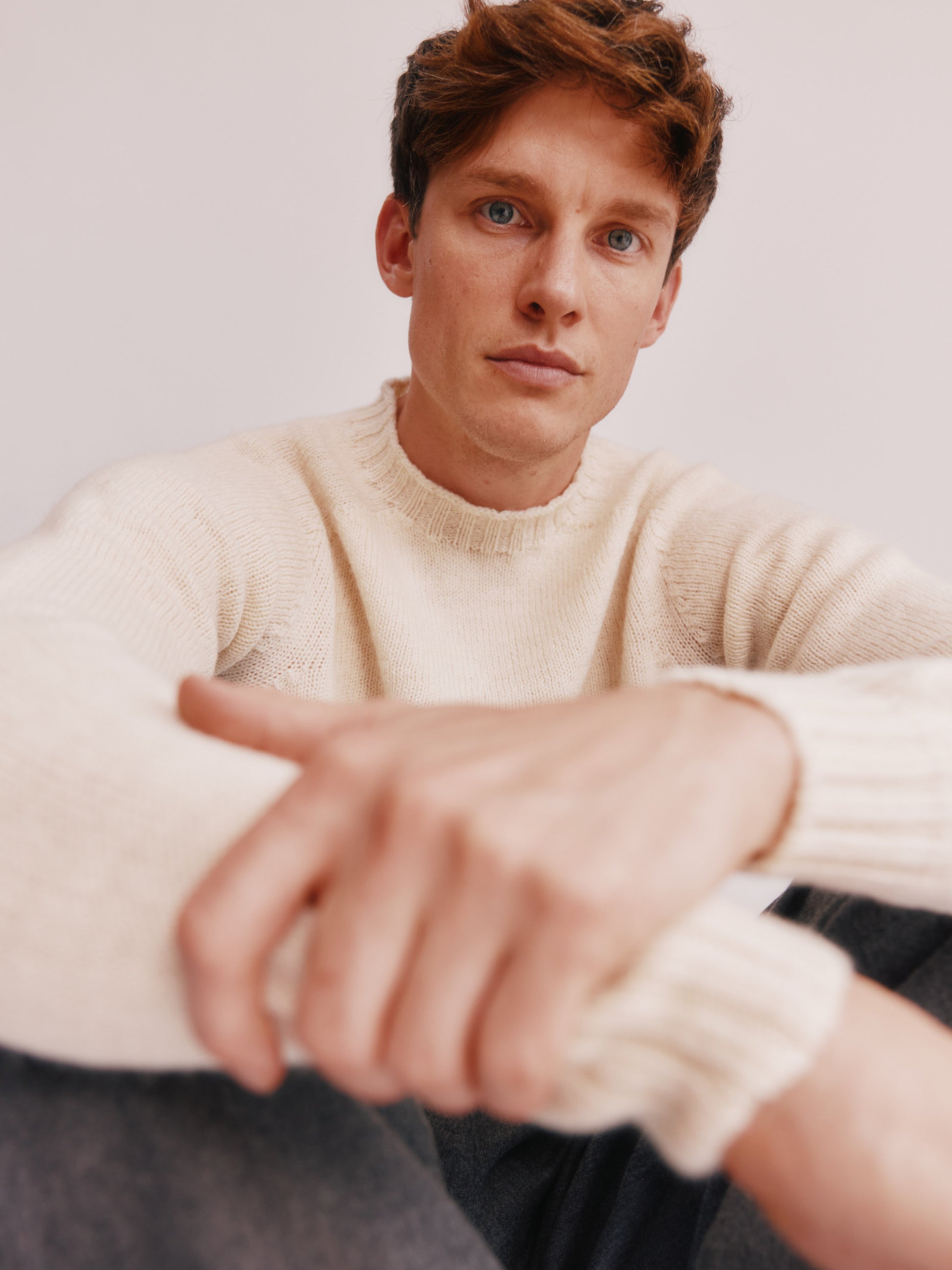 Photograph of a model wearing a 
Bosie Knitwear Harley of Scotland undyed seamless saddle shoulder men's Sherpa 2 ply Voe True Shetland sweater jumper in Ecru White.