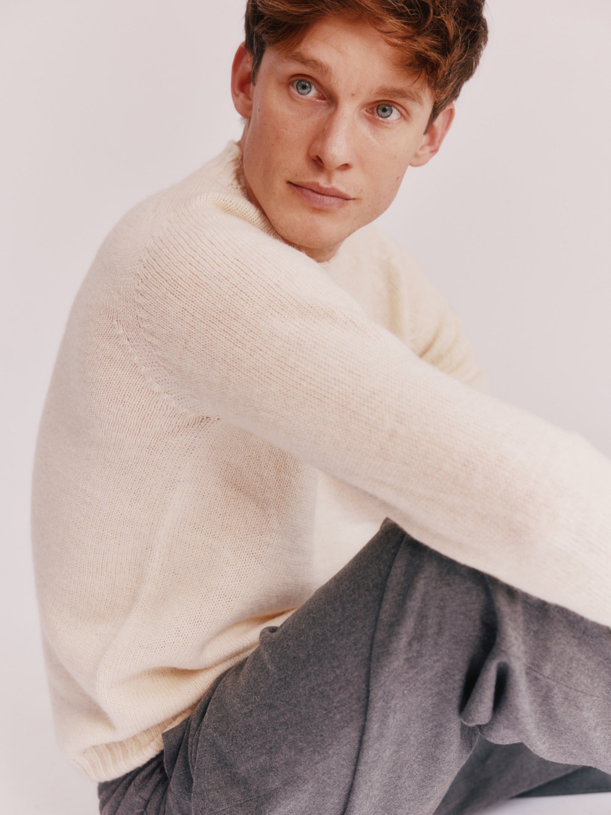 Photograph of a model wearing a 
Bosie Knitwear Harley of Scotland undyed seamless saddle shoulder men's Sherpa 2 ply Voe True Shetland sweater jumper in Ecru White.