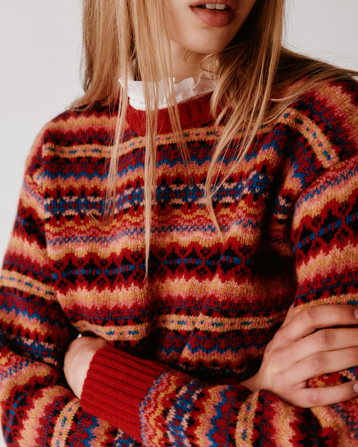 A model wearing a Bosie Cropped Allover Fair Isle Women's Sweater in colour French Red.