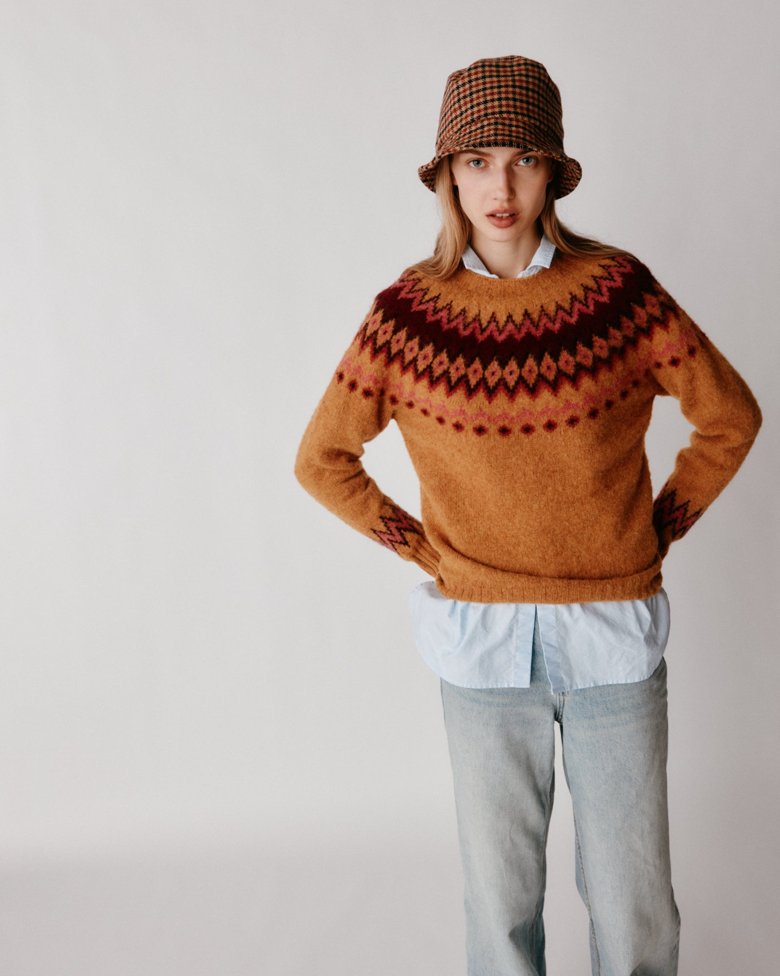 A model wearing a Bosie Fjord Yoke Brushed Fair Isle Women's Lambswool Sweater in colour Gold Dust / Cummin.