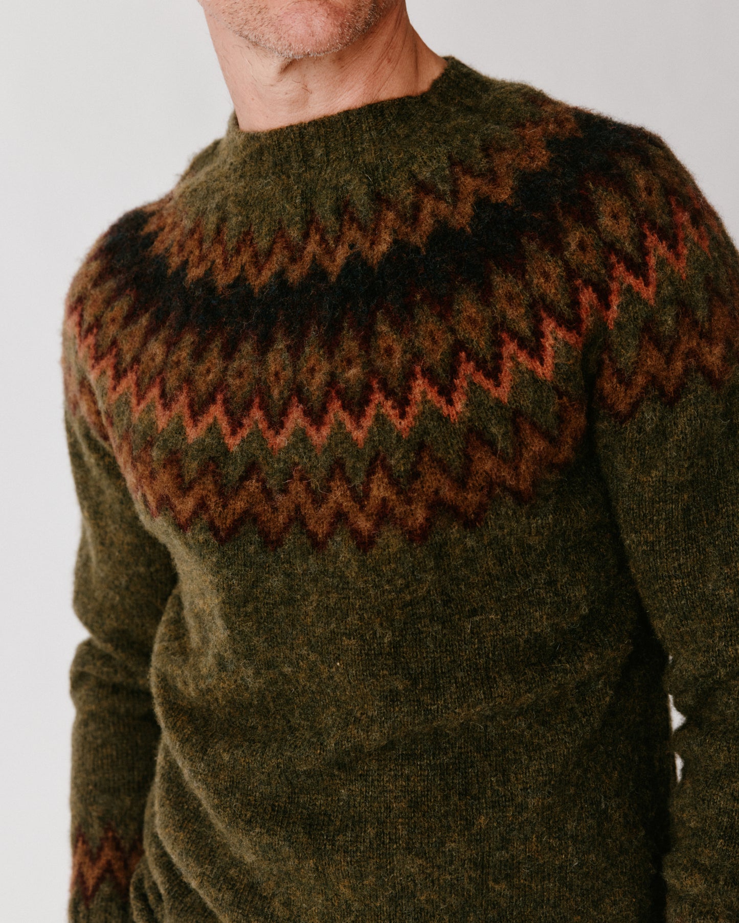 A model wearing a Bosie Glacier Yoke  Brushed Fair Isle Men's Sweater in colour Scots Pine / Pineshadow.