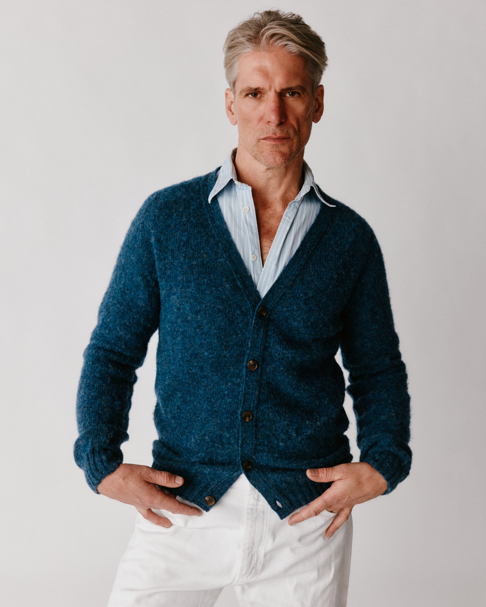 A model wearing a Bosie Harley of Scotland Shaggy Shetland Men's V Cardigan in colour Denim.