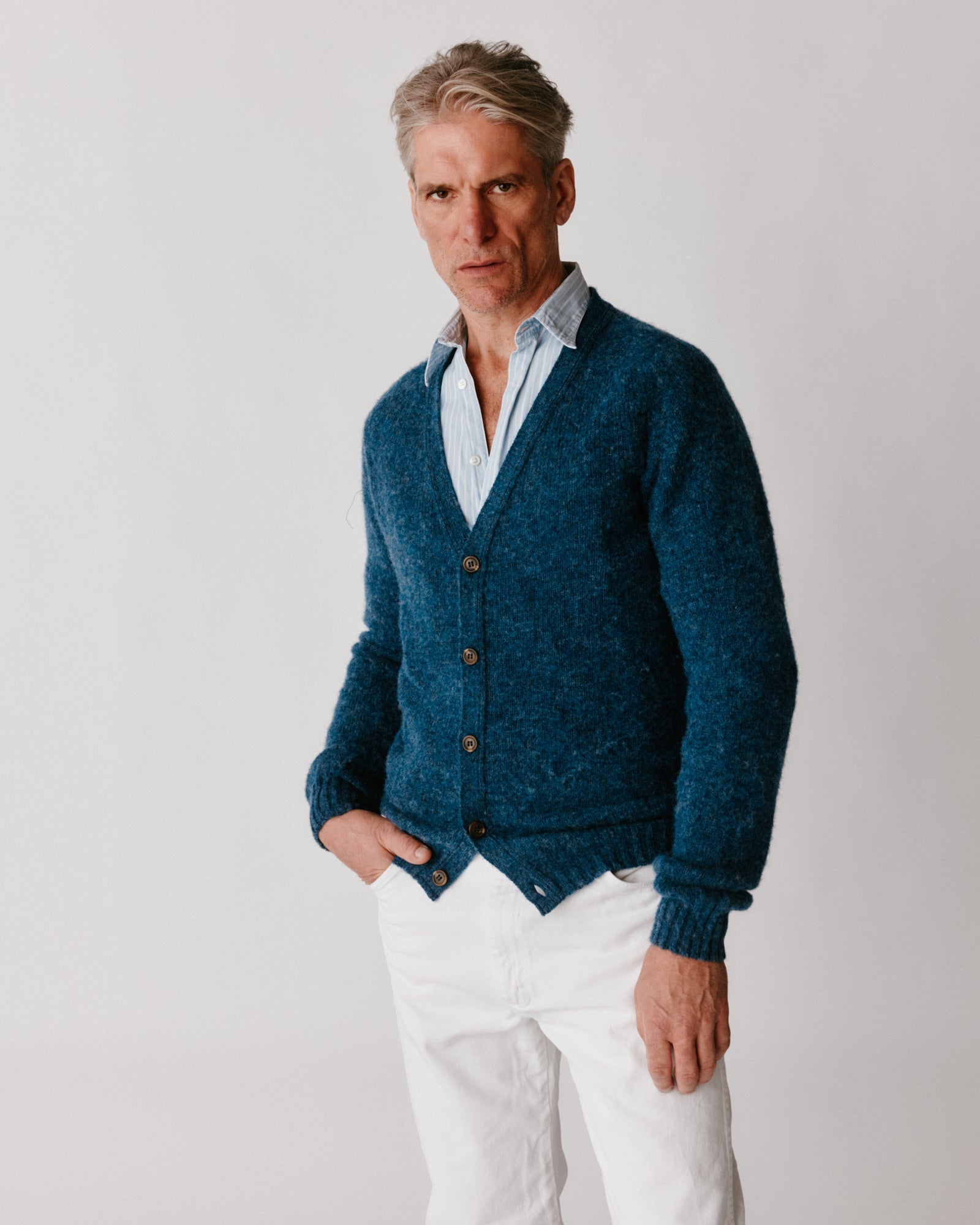 A model wearing a Bosie Harley of Scotland Shaggy Shetland Men's V Cardigan in colour Denim.
