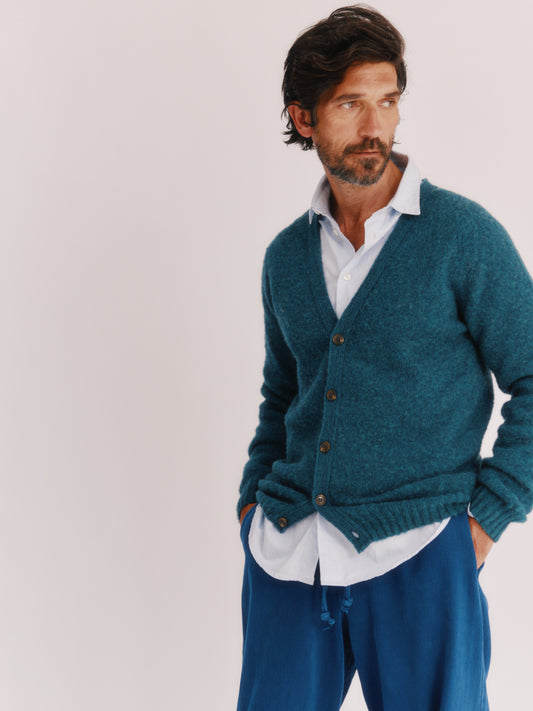Model wearing a Harley of Scotland Shaggy Shetland Men's V Cardigan in colour Storm Dark Teal. 