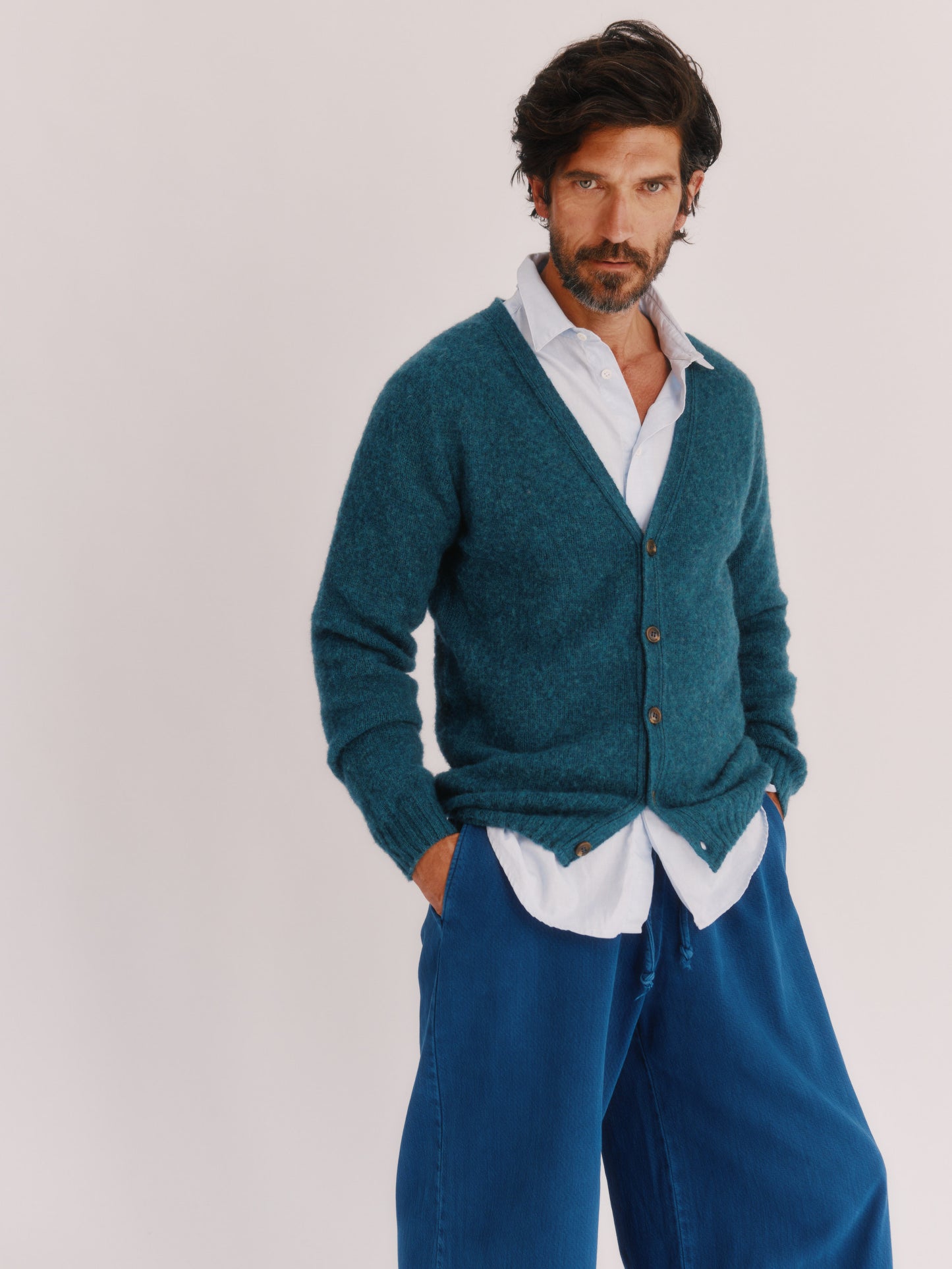 Model wearing a Harley of Scotland Shaggy Shetland Men's V Cardigan in colour Storm Dark Teal. 