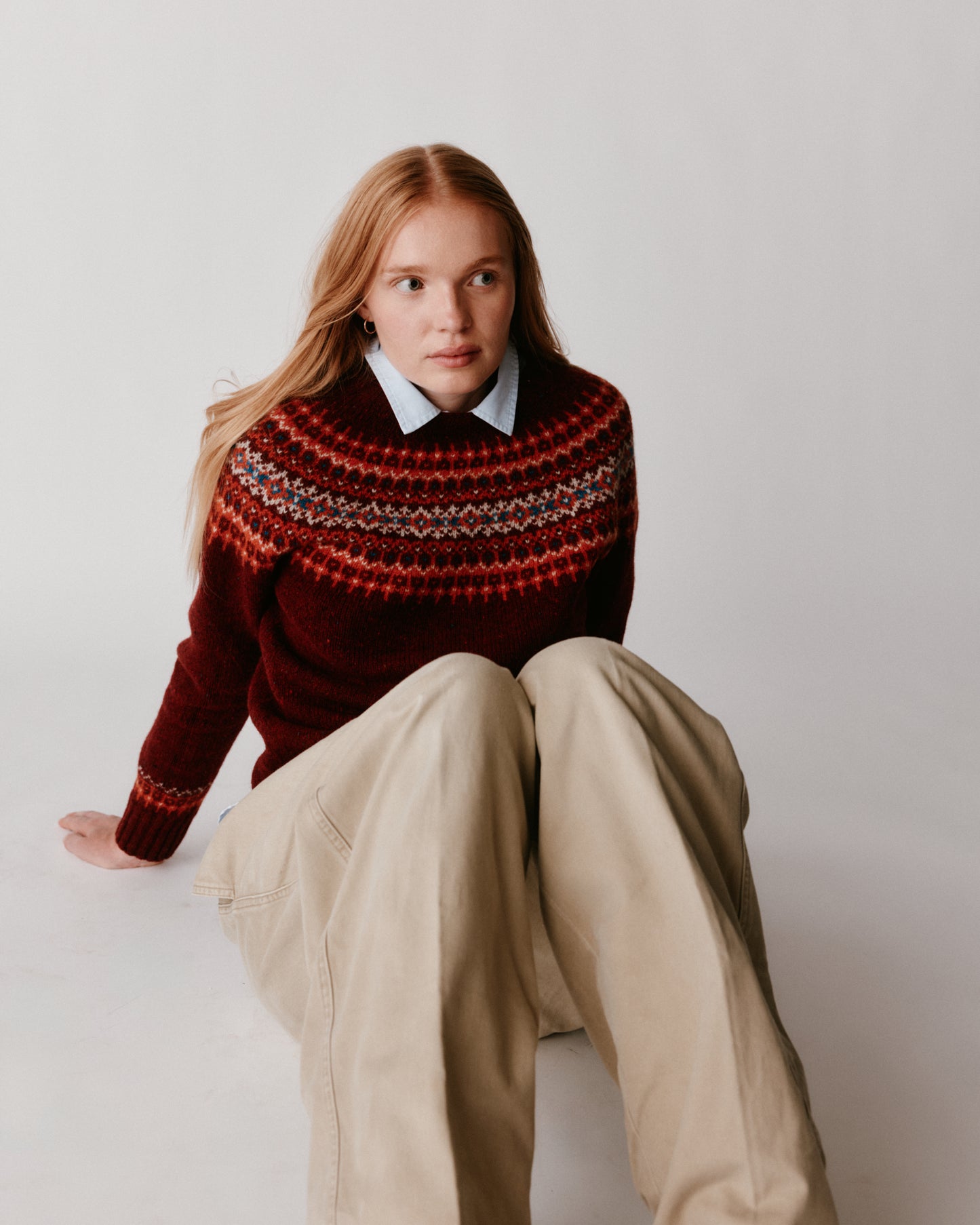 A model wearing a Bosie Islander Yoke Fair Isle Glenugie Nep Women's Sweater in colour Tiree Red.