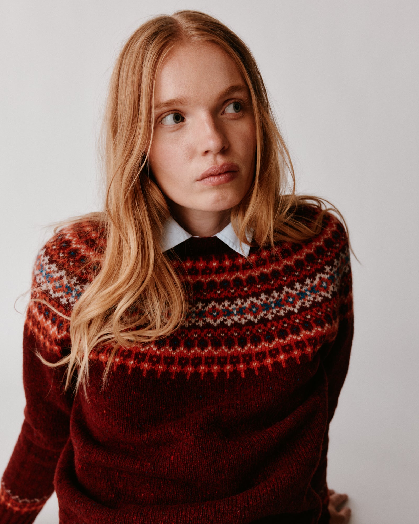 A model wearing a Bosie Islander Yoke Fair Isle Glenugie Nep Women's Sweater in colour Tiree Red.