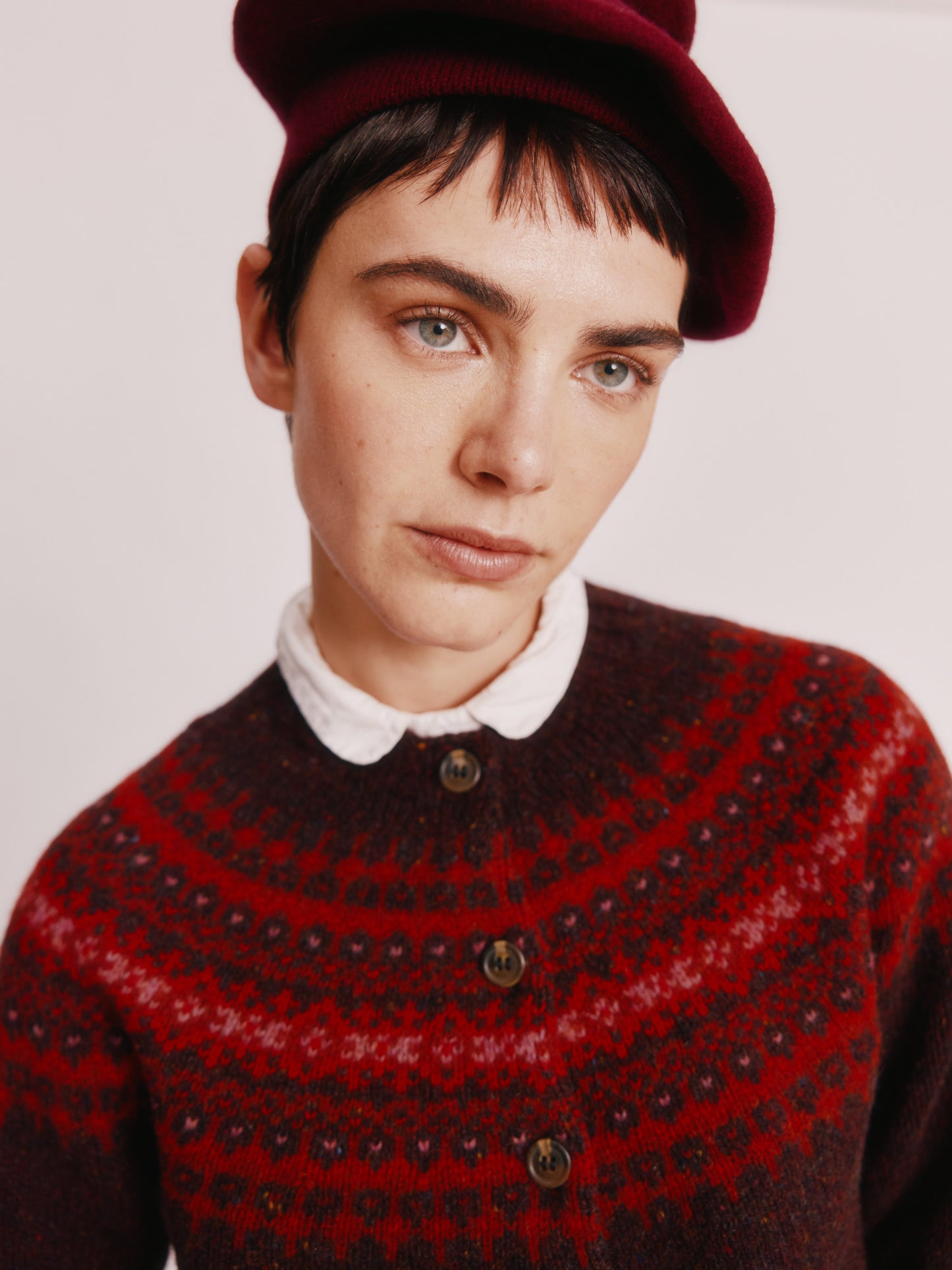 Model wearing a Bosie Knitwear Islander Yoke Fair Isle Glenugie Women's Cardigan in colour Lewis Dark Aubergine.