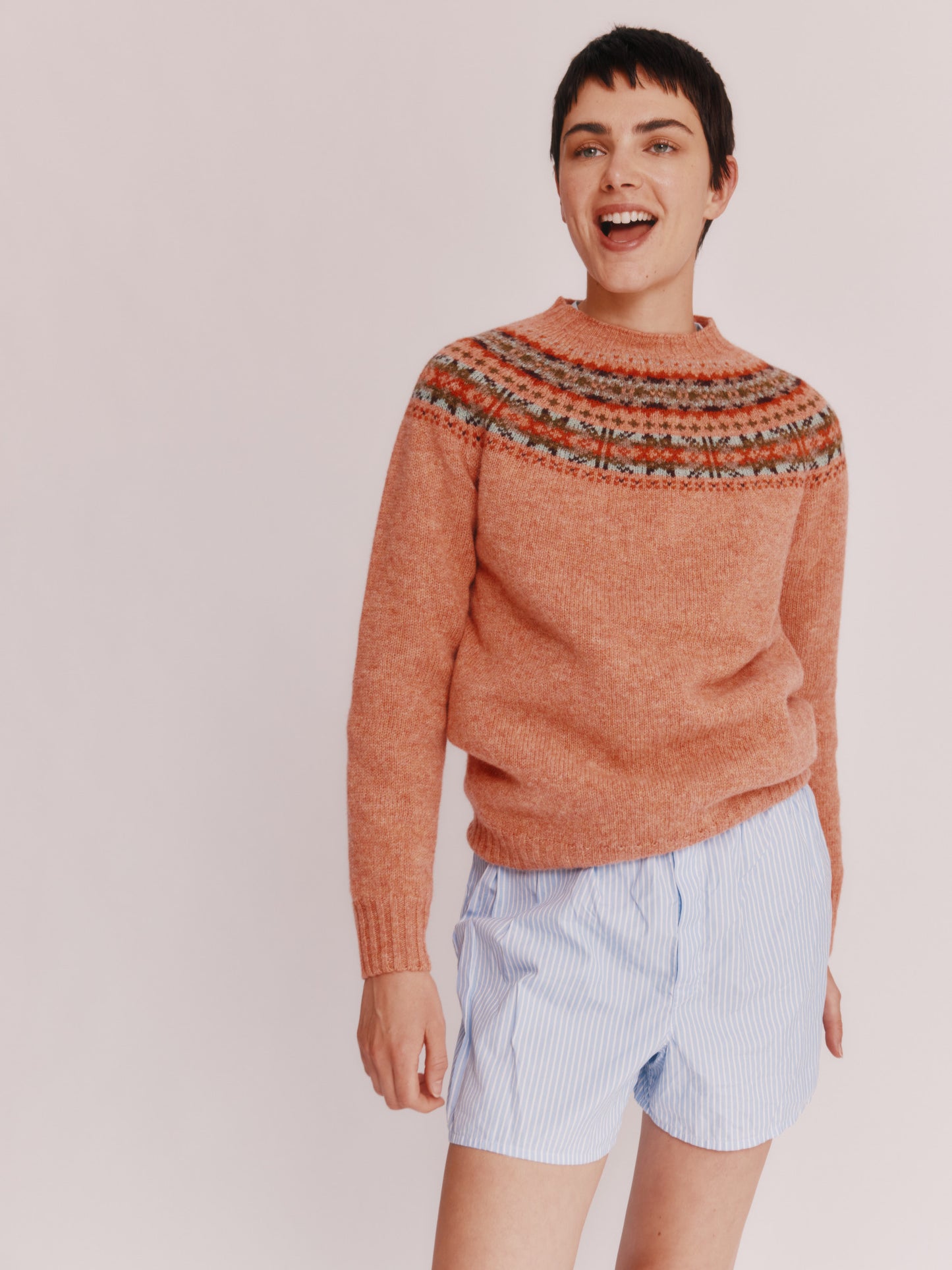 Model wearing a Skye Yoke Fair Isle Women's Sweater  in colour Parfait Peach. 