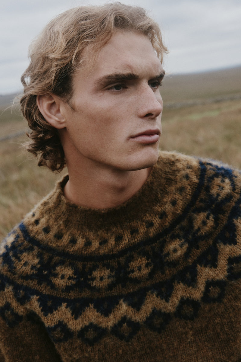Man wearing a brushed Bosie Fair Isle yoke sweater in brown and navy on the Scottish moors – men's knitwear, made in Scotland