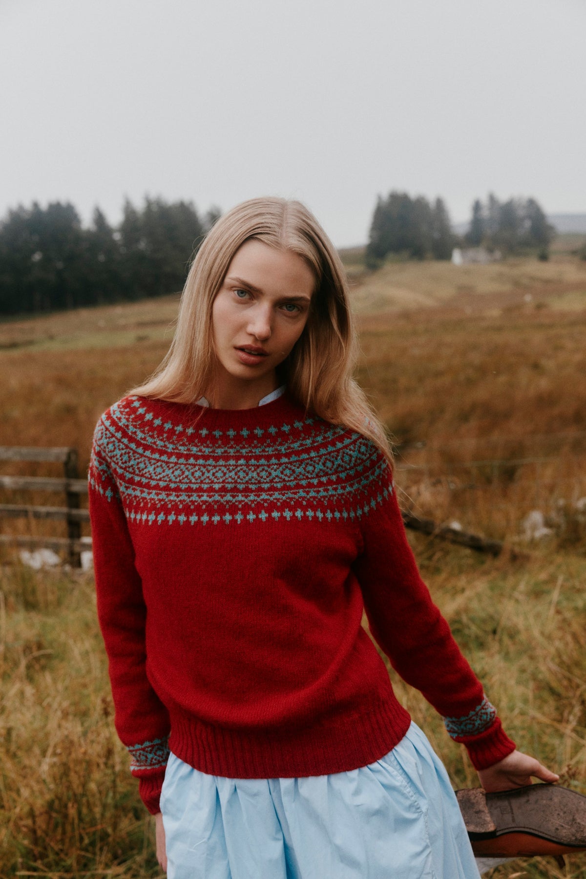 Model wearing the Bosie Hara Yoke Fair Isle Women's Sweater in French Red on a Scottish moor – seamless, seam-free pure wool, knitted in Scotland by Harley of Scotland for Bosie Knitwear