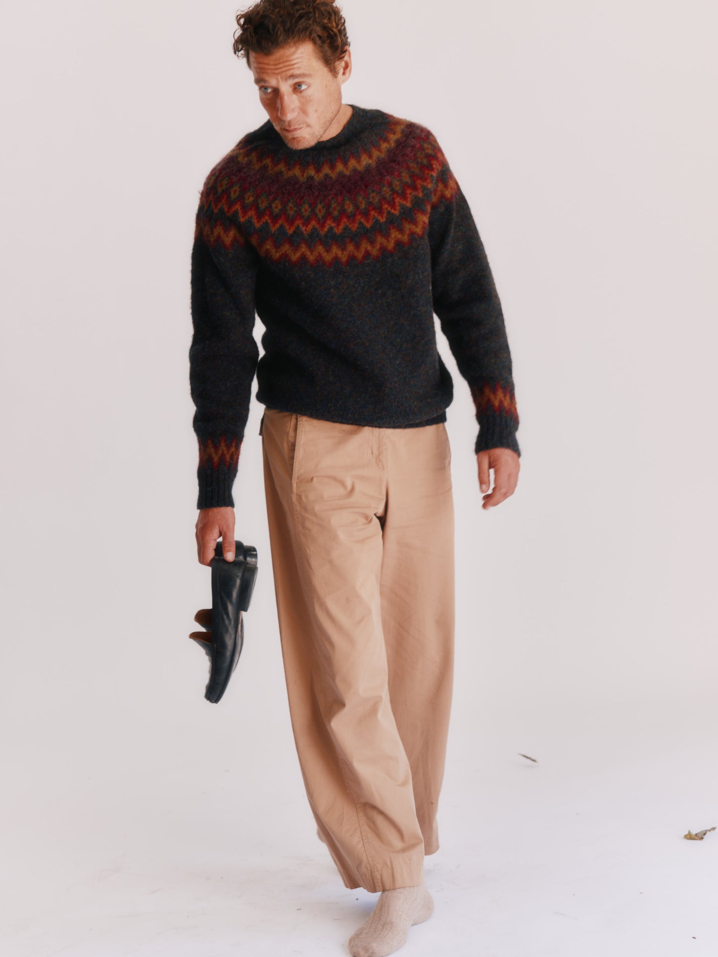Man wearing a Bosie Fjord Nordic patterned sweater and beige pants on a white background