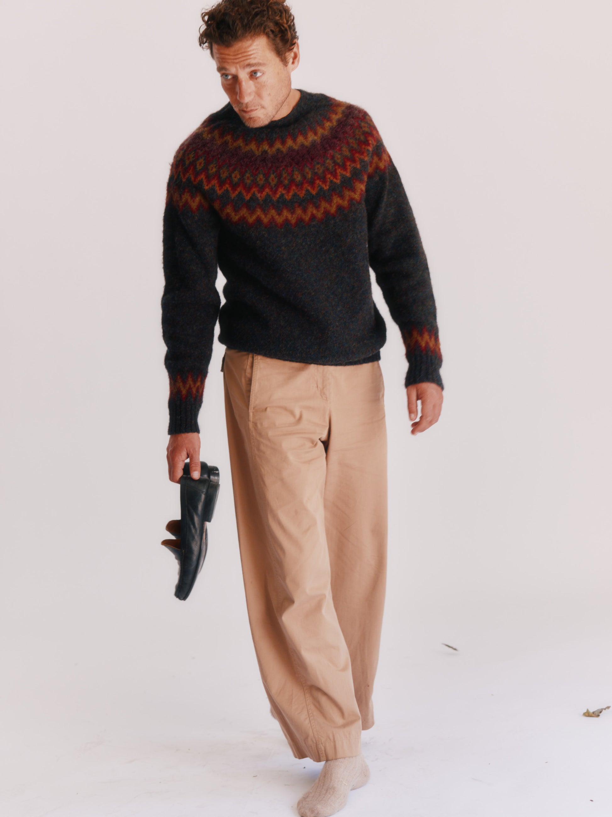Man wearing a Bosie Fjord Nordic patterned sweater and beige pants on a white background