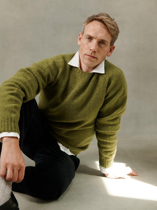 Man wearing a Bosie Knitwear Harley of Scotland seamless saddle shoulder men's Shetland sweater jumper in Olive Grove Green